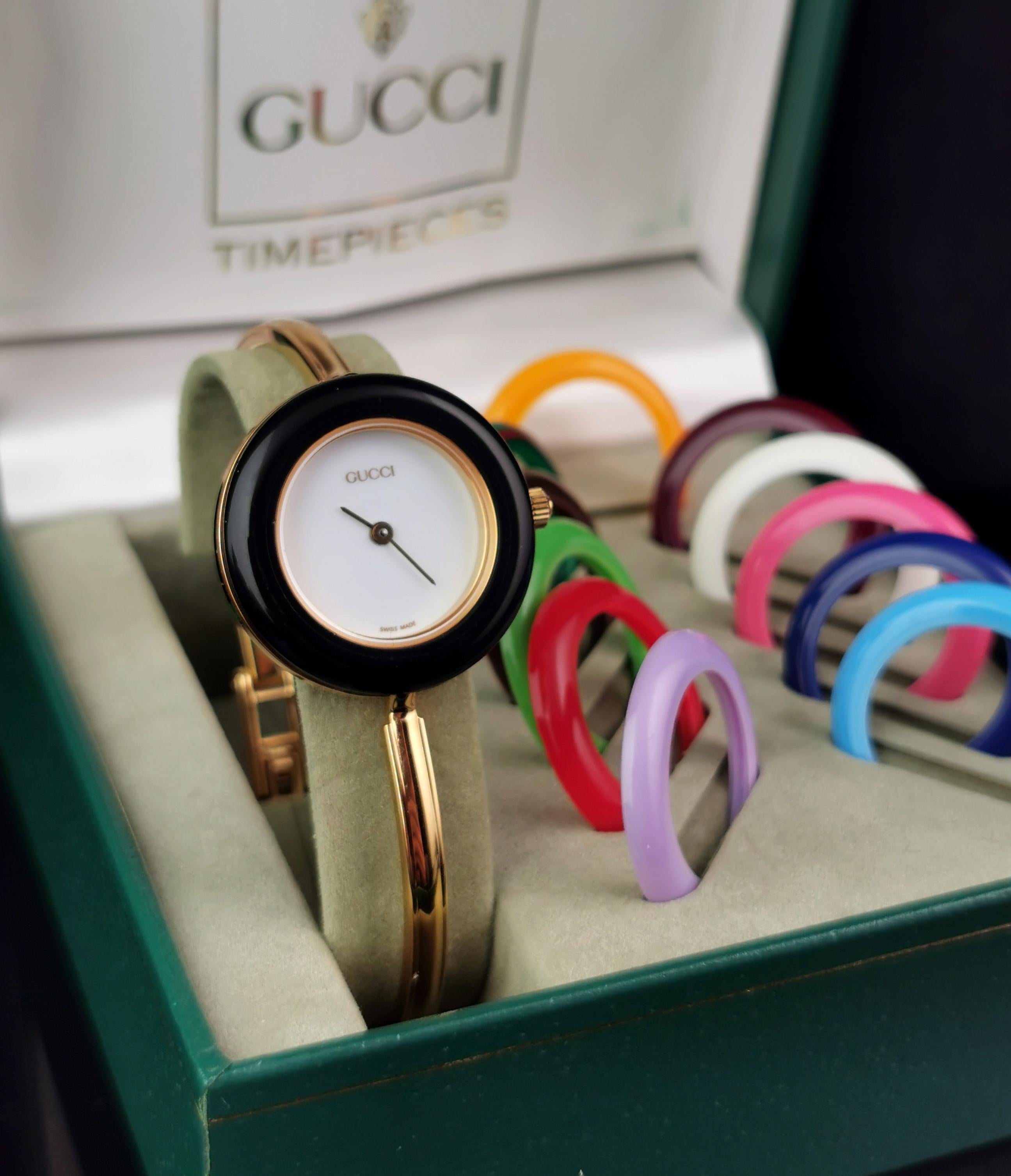A stylish Gucci 11/12.2 gold plated wristwatch. 

This is a bangle strap watch with a nice sleek gold plated mariner link. 

The case is gold plated and the watch has interchangeable bezels in different colours with there being 12 colours in total.