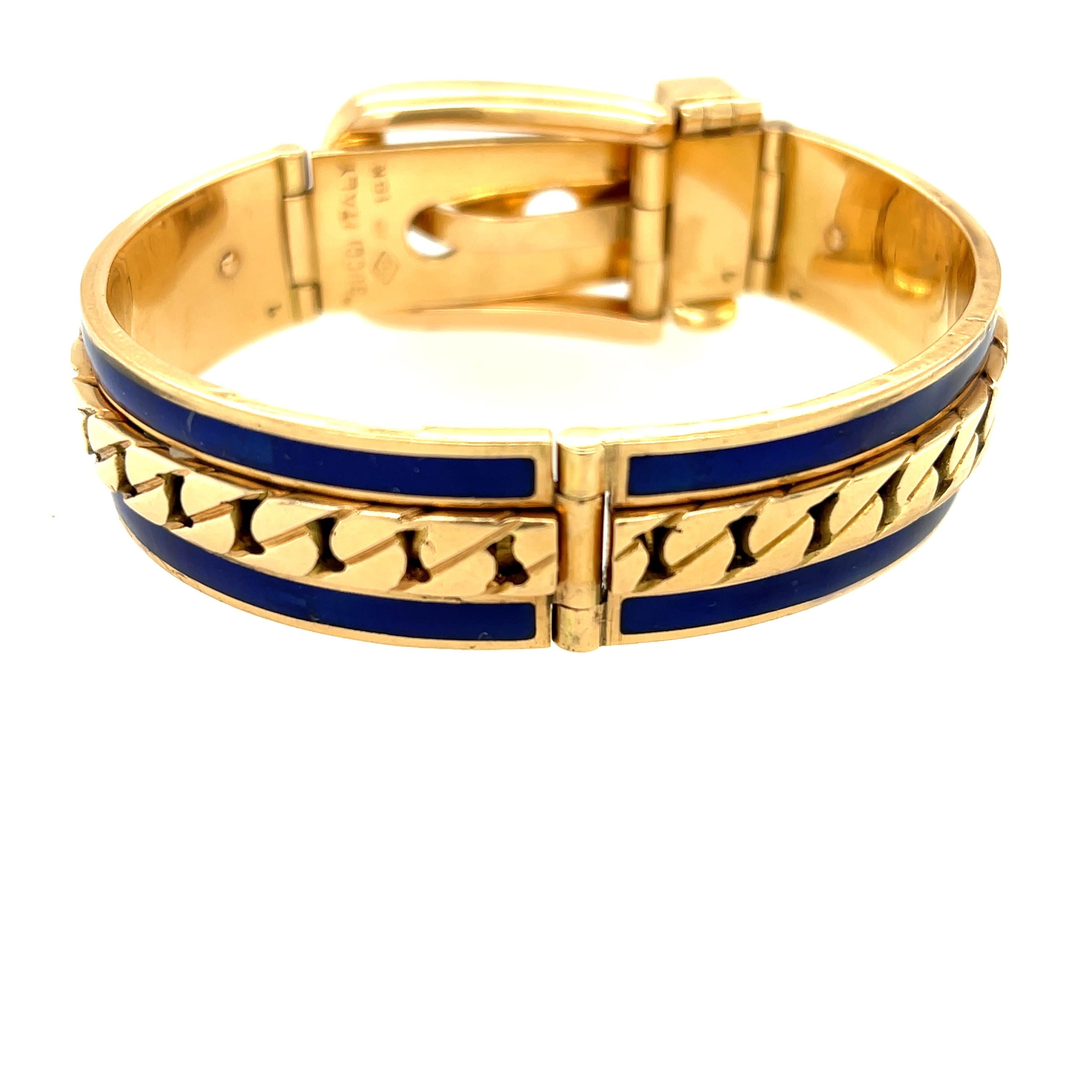A vintage 18k gold and blue enamel buckle bracelet by Gucci circa 1970. This bracelet has the classic Cuban link detail on the sides of the bangle, between two stripes of blue enamel. The bracelet is made like a belt, with a working buckle. The