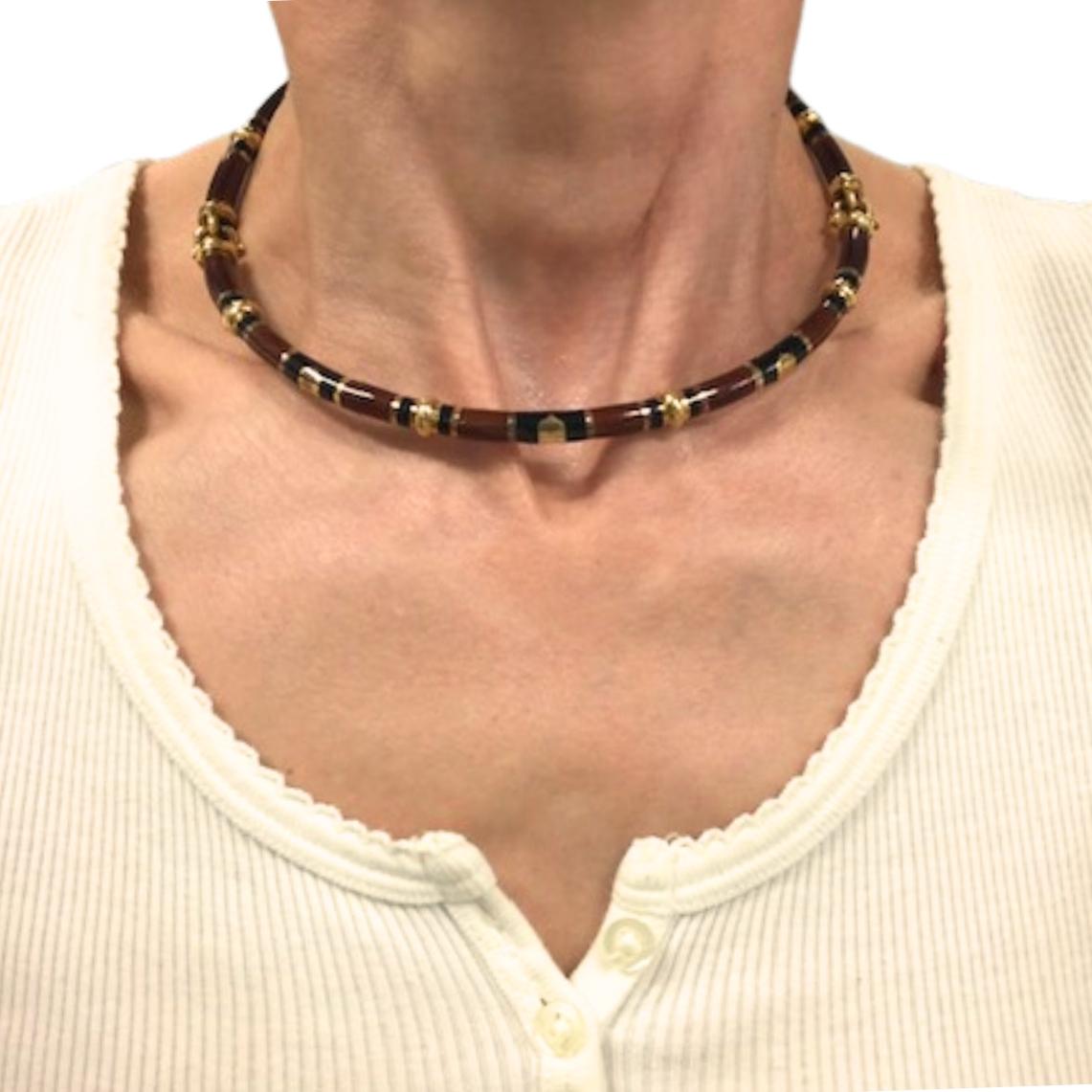This chic vintage Gucci necklace is crafted in 18k gold with rich enamel detailing. The design features alternating segments of deep red and black enamel, accented with polished gold connectors. The circular form is enhanced with gold links placed
