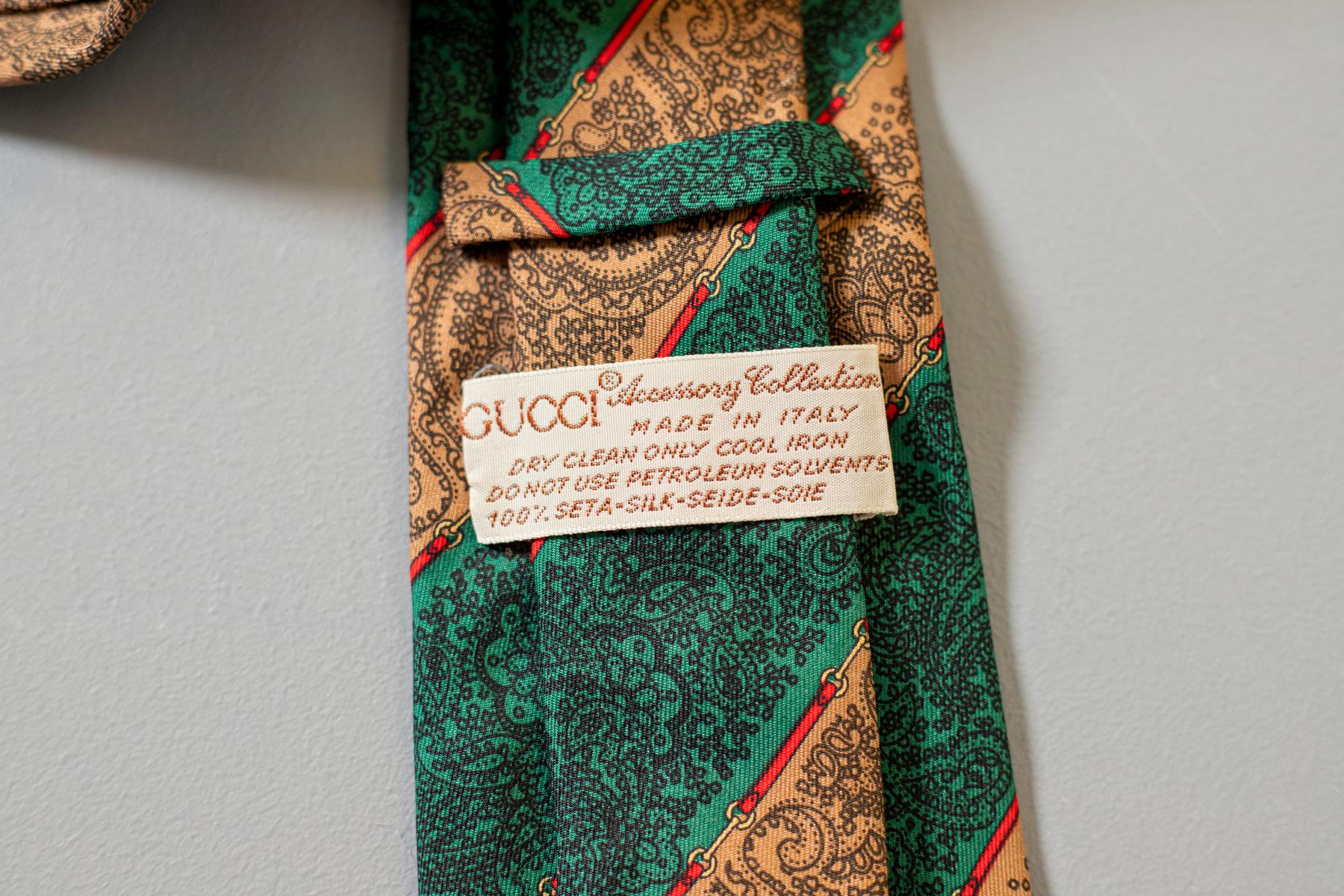 Ein schwarzes Paisleymotiv auf einem gestreiften Hintergrund in Grün und Beige: Diese Krawatte schreit in jeder Hinsicht nach Gucci. Diese Krawatte aus reiner Seide ist ein Evergreen: Sie ist die perfekte Wahl für einen eleganten und doch