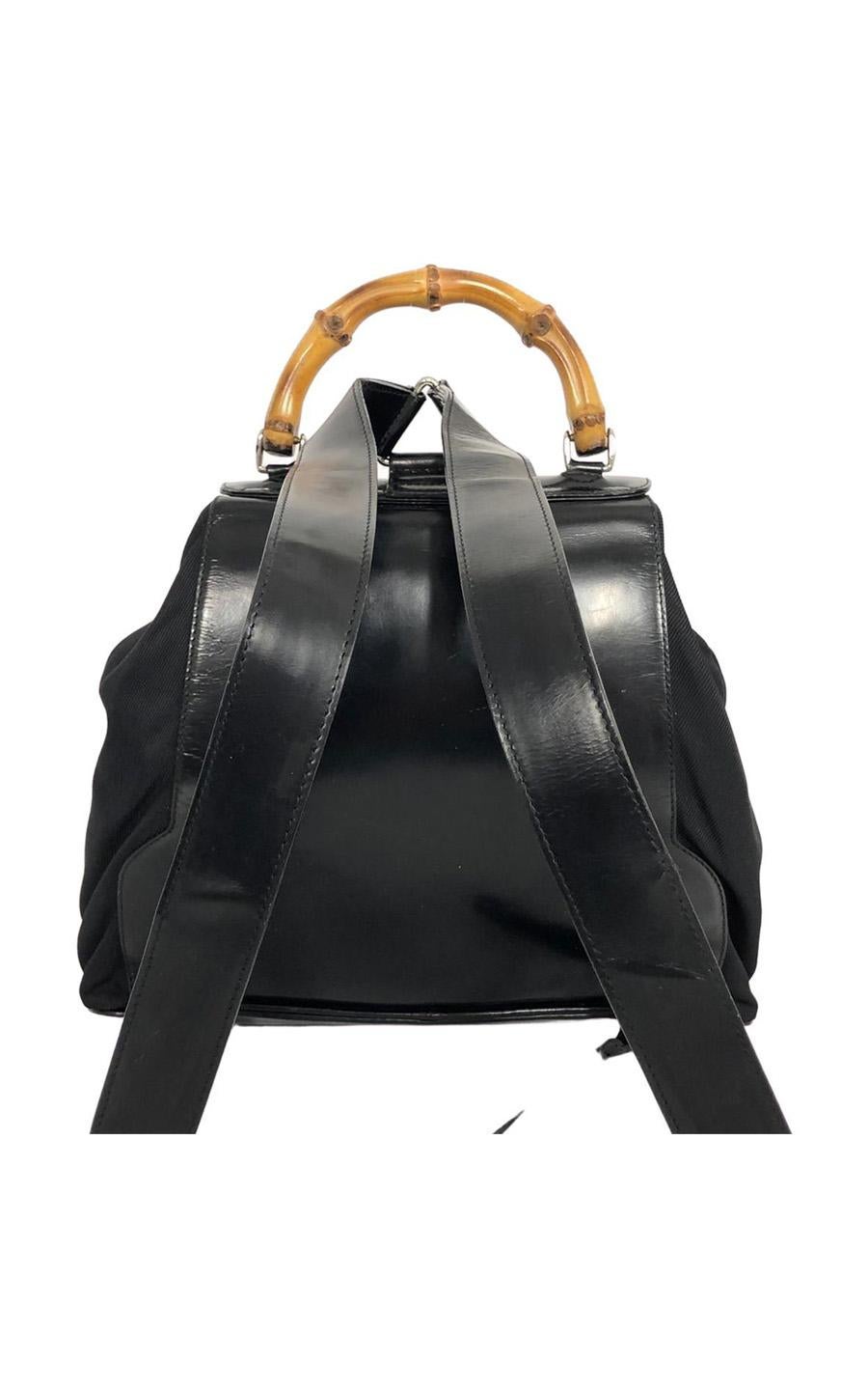 Gucci Bamboo Backpack, size big, in black Cloth wit patent leather details. Characteristic of this bag is the famous curved bamboo handle at the top of the bag. The hardware is silver-colored. The bag closes with a belt buckle and a leather