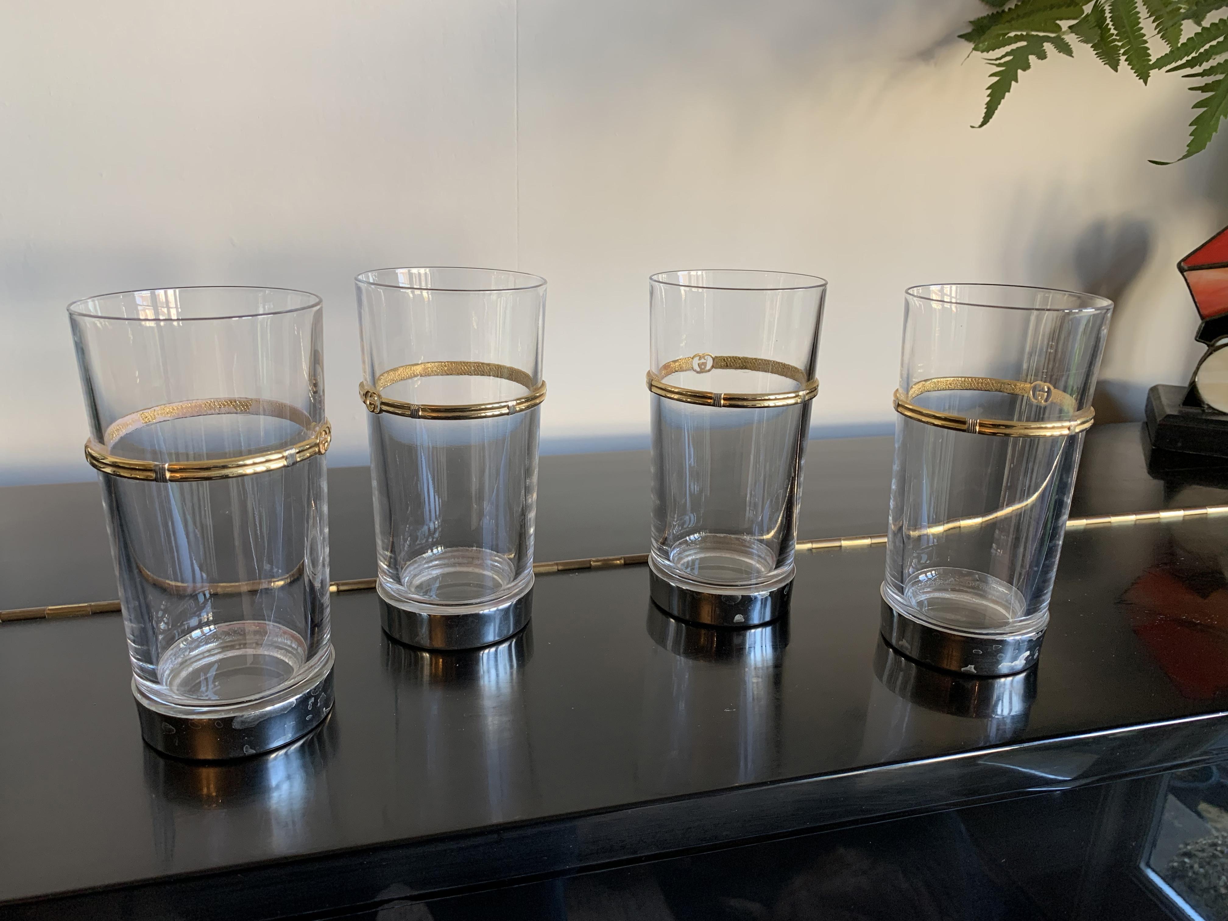 Vintage Gucci barware set of 4 Highball tumbler glasses. Crystal with Gold band with GG logo, silver plated base. Made by Gucci in Italy, stamped on base. Mid century 1970s. There are some light marks /scratches/ discoloration consistent with age,