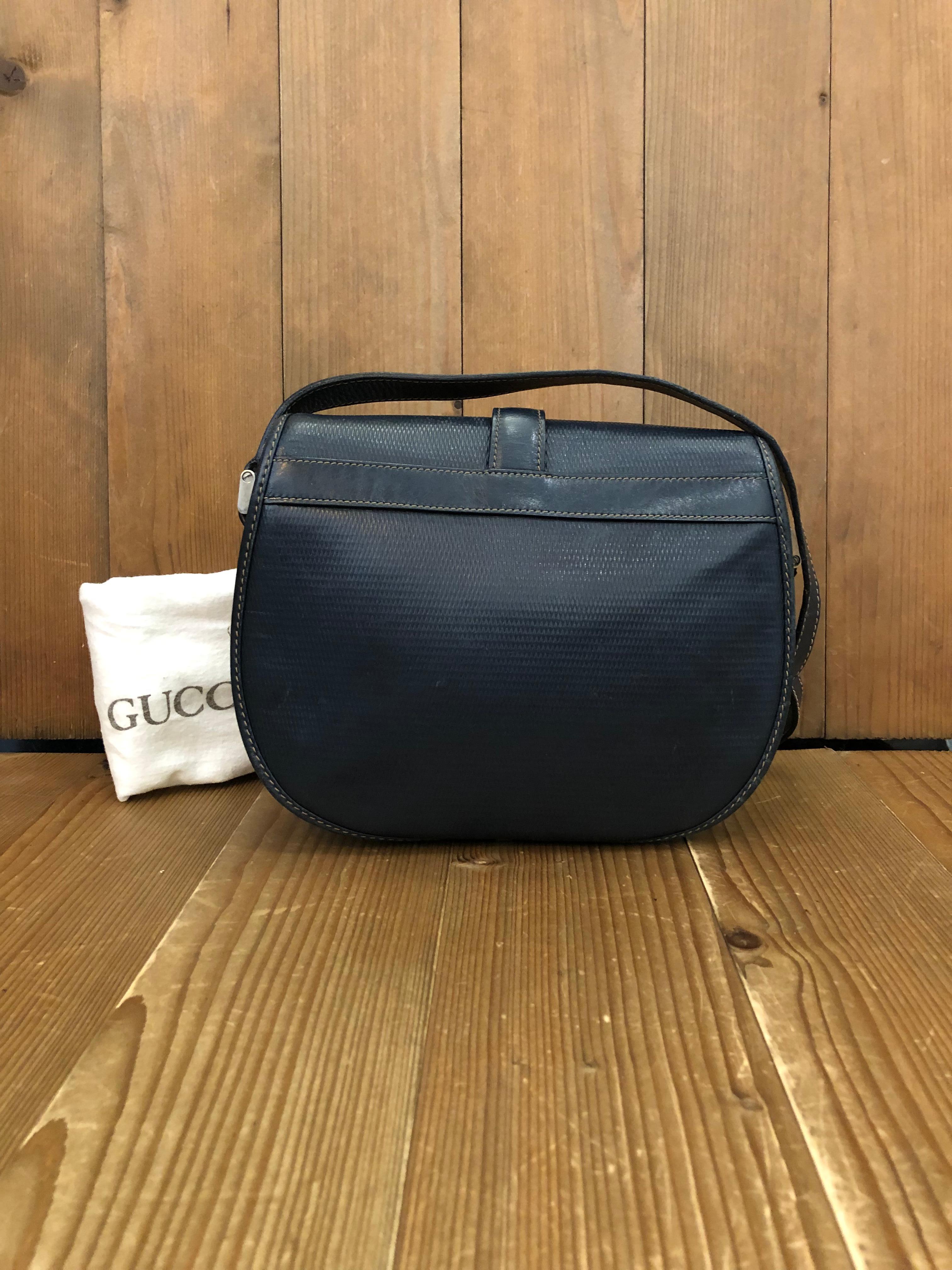 This vintage GUCCI crossbody bag is crafted of textured calfskin leather in navy with equestrian accent. Front flap closure open to a suede interior in navy with one zippered pocket. Made in Italy. Measures approximately 7.5 x 7 x 2.25 inches Drop
