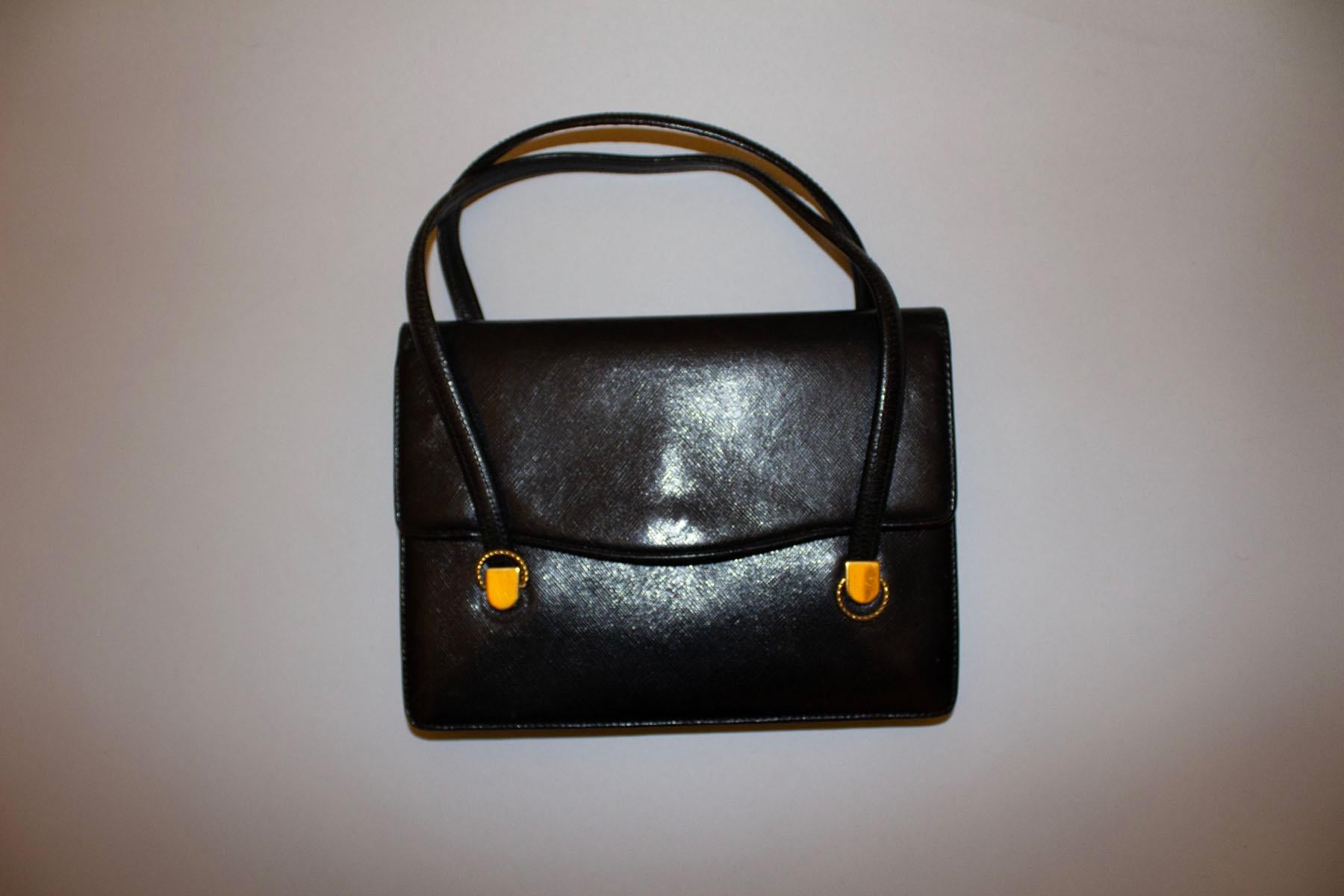 A chic , black leather vintage handbag by Gucci.
Dating from the 1960s, the bag has attractive gilt detail on the front,and internal zip pocket and two internal pouch pockets. It fastens with a popper at the front and has two handles. 
Measurements: