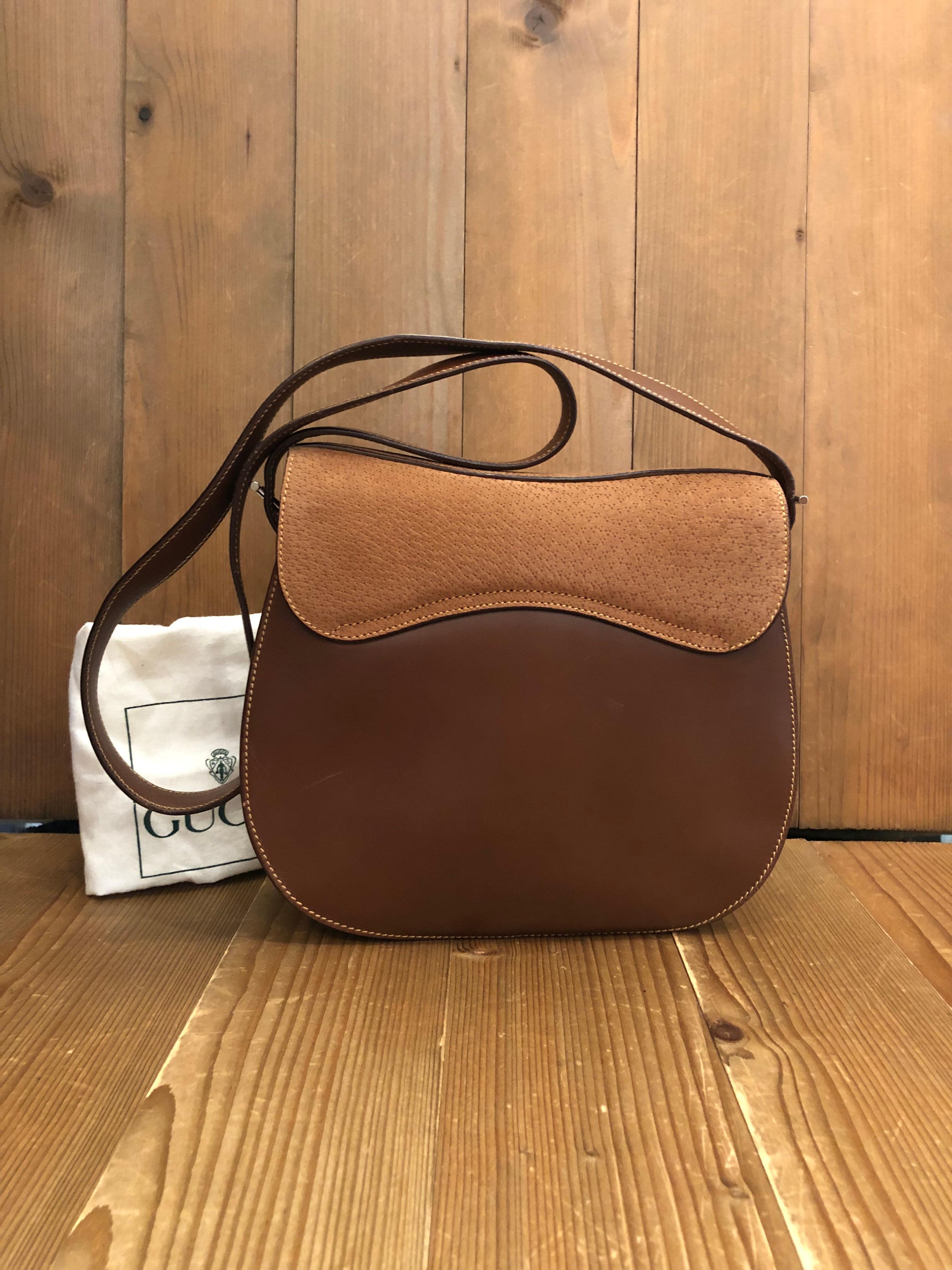 This vintage GUCCI mini saddle bag is crafted of smooth calf leather and nubuck in brown and silver toned hardware. Front magnetic snap closure opens to a brown suede interior featuring a zippered pocket. Made in Italy. Measures approximately 9 x 8