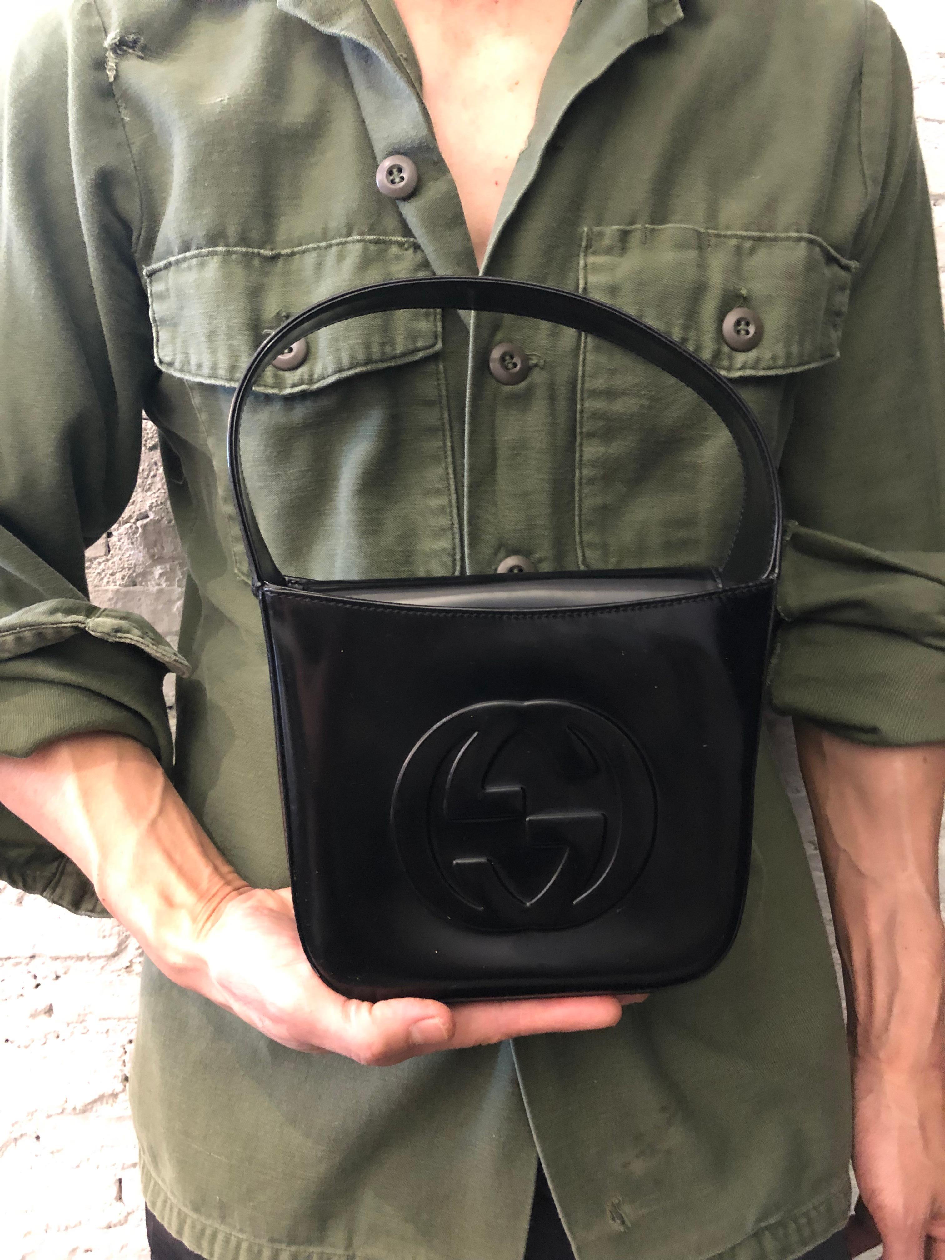 This vintage GUCCI Mini Hobo Handbag is crafted of smooth calfskin leather in black featuring a massive GG interlock Impression at the front. Top flap magnetic snap closure opens to a coated interior which has been professionally cleaned featuring a