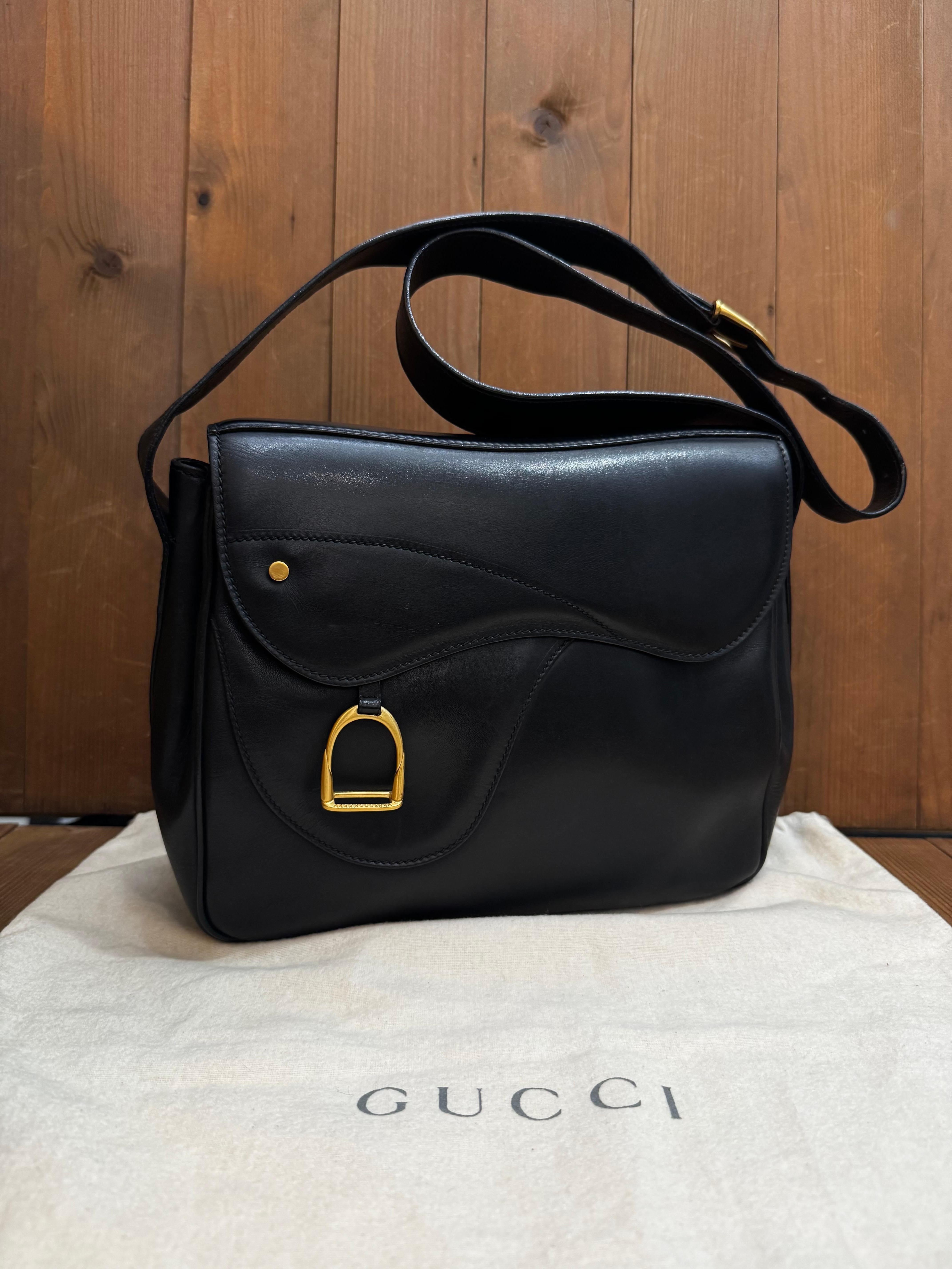 Cette sacoche vintage de Gucci a été réalisée en cuir de veau noir et est ornée de ferrures dorées. Le rabat avant à double fermeture magnétique décoré d'un charme d'étrier s'ouvre sur un intérieur en jacquard diamanté de couleur bordeaux comprenant