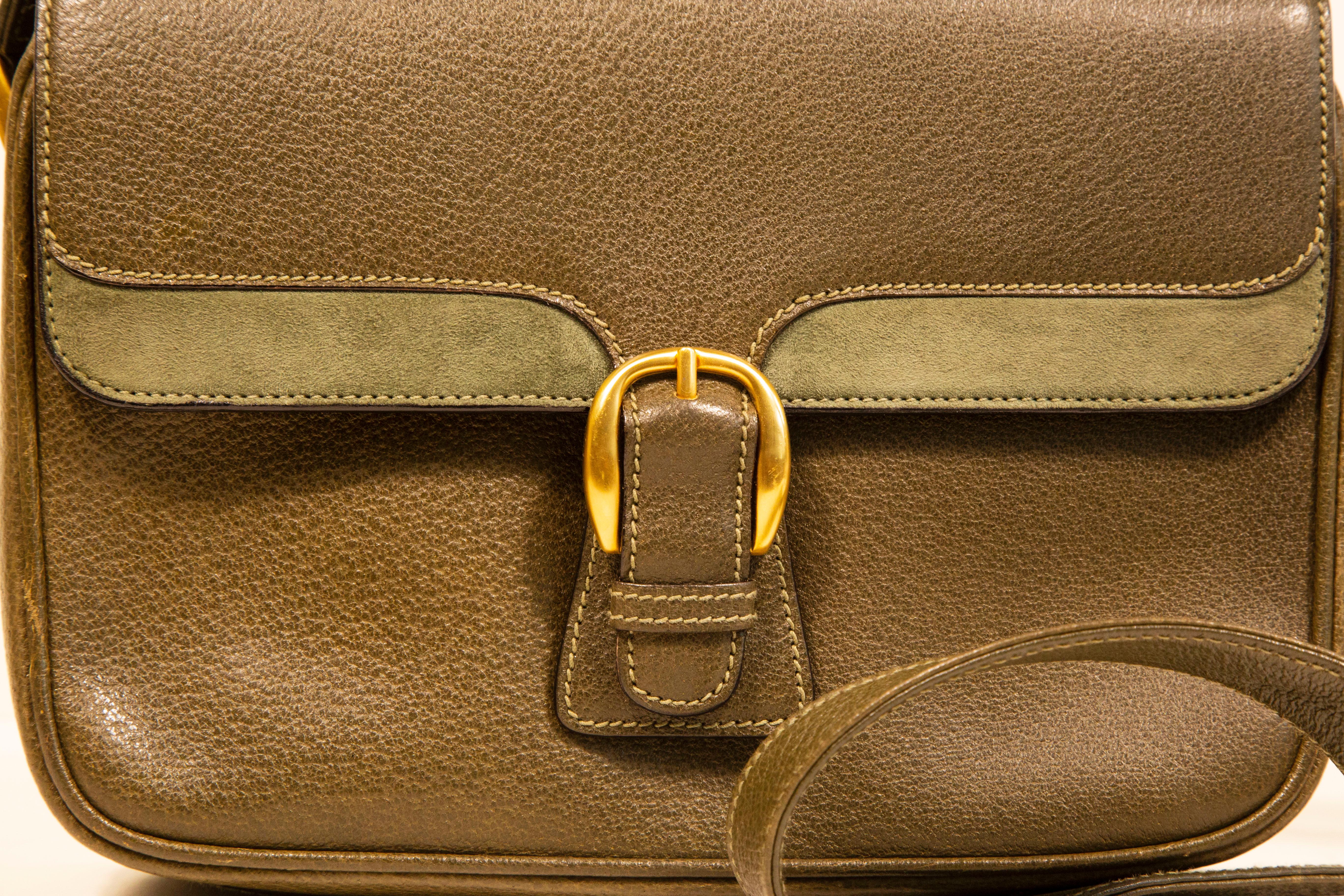 A vintage Gucci crossbody bag. The bag is made of olive green slightly textured leather with green suede application at the front flap, and gold toned hardware. The interior is lined with brown leather and next to the major compartment it features