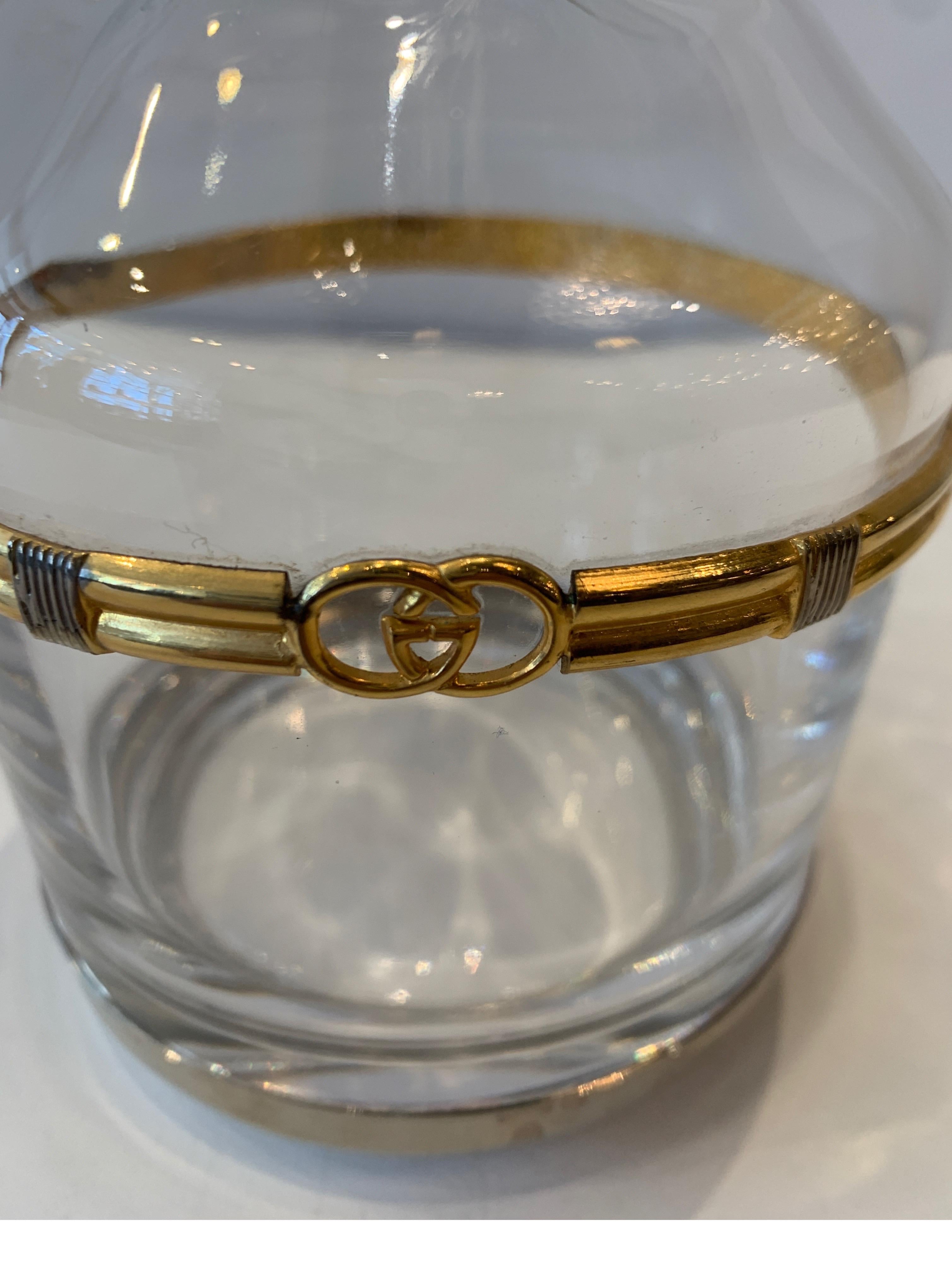 A 1960s Gucci crystal decanter with gilt logo mount. The water clear European crystal with the original round stopper with a double band mount with Gucci logo. The bottle form with panel cut neck. Measure: 12 inches tall.