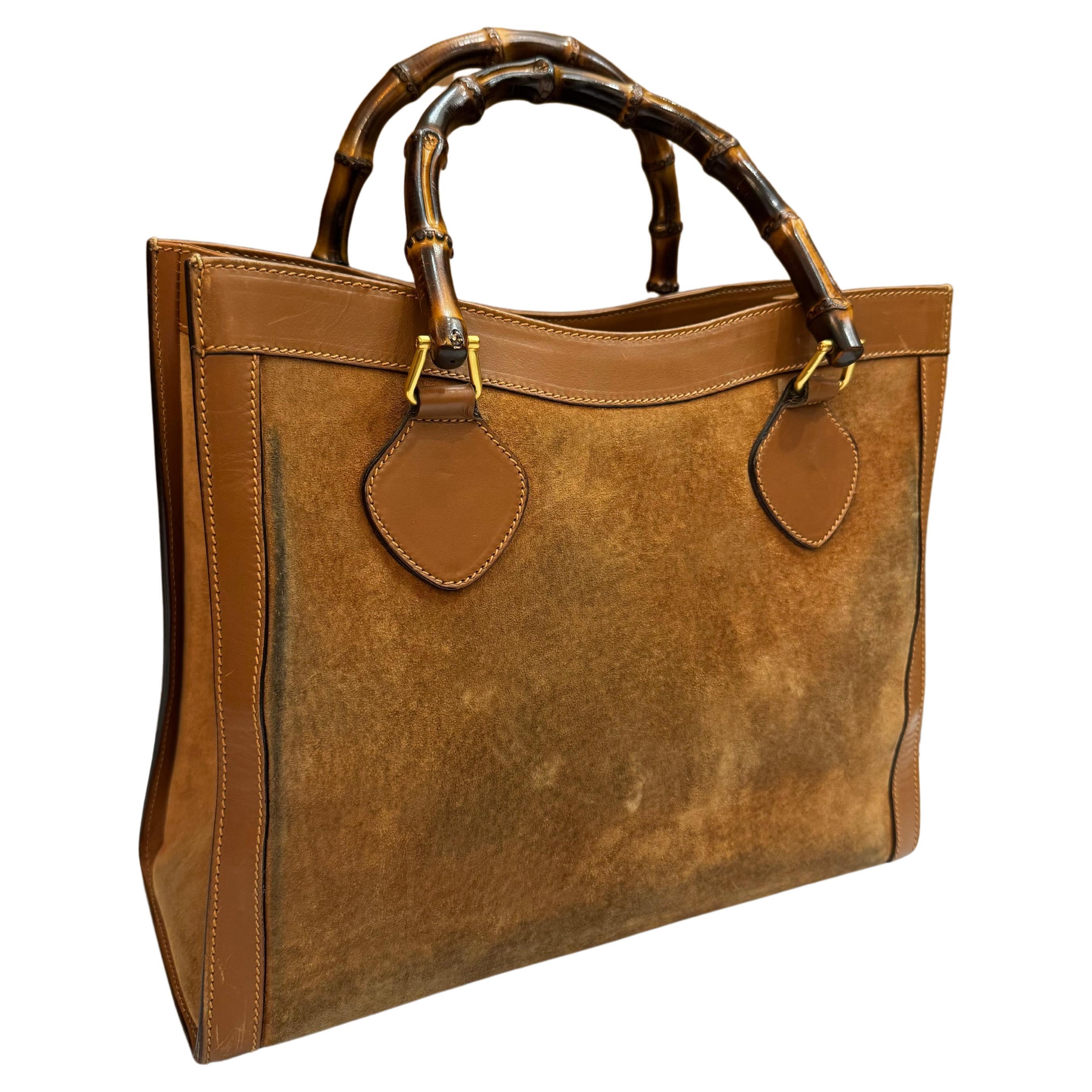 This vintage GUCCI Diana bamboo tote is crafted of nubuck and smooth calfskin leather in brown featuring matt gold toned hardware and bamboo handles. Wide top opens to a brown nubuck leather interior featuring a zippered pocket. This is a rare Gucci
