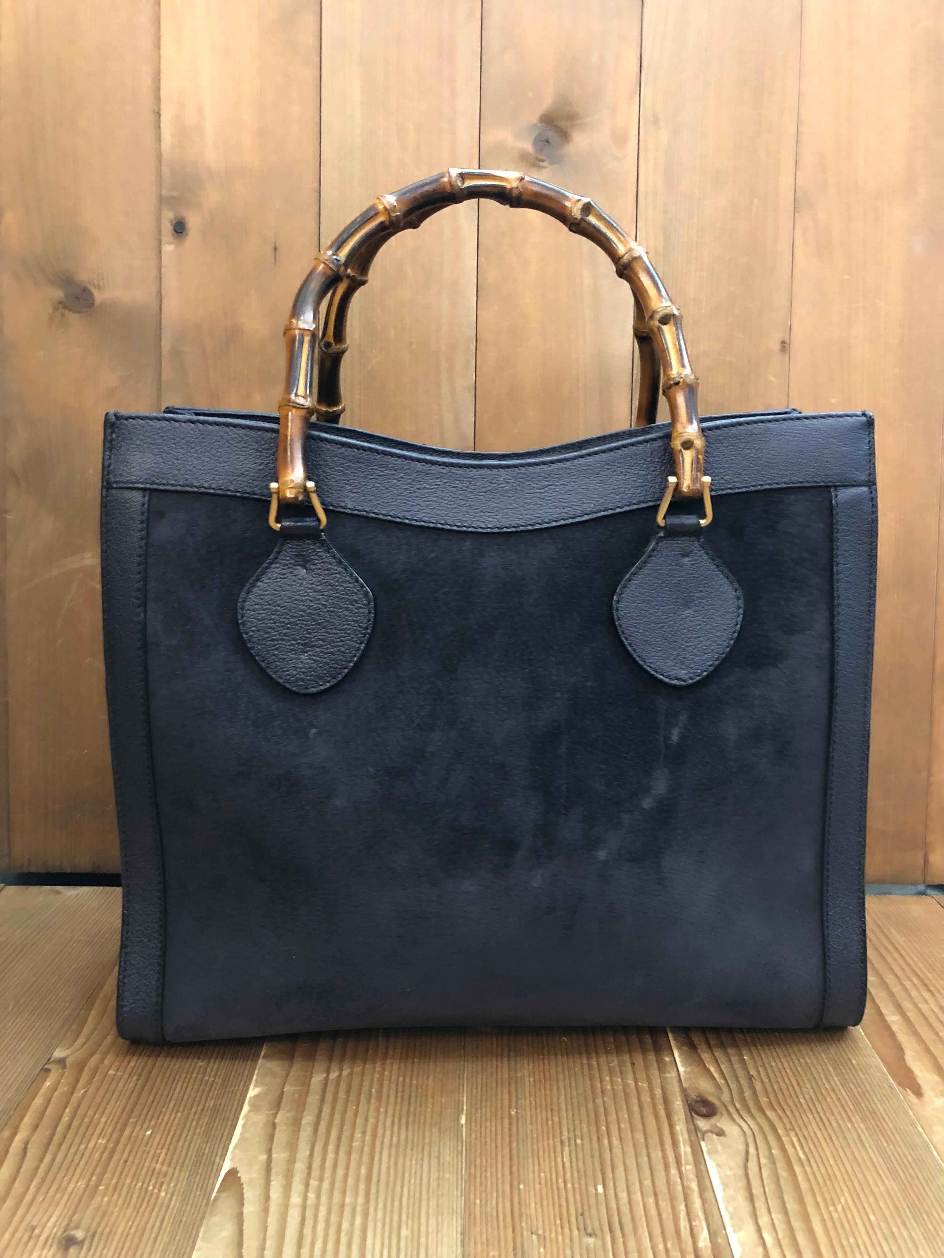 This vintage GUCCI Diana bamboo tote is crafted of pigskin’s leather and nubuck in navy featuring matt gold toned hardware and bamboo handles. Top magnetic snap closure opens to a new interior in black featuring two main compartments with one