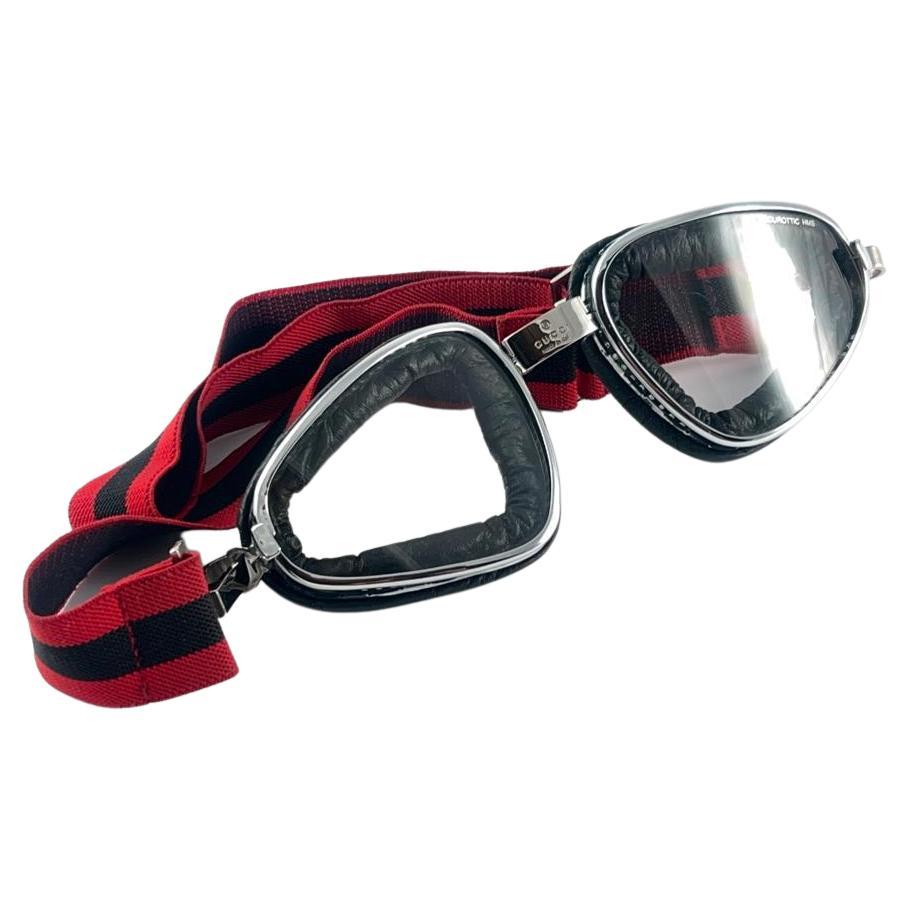 Superb Item! 2000's Gucci silver goggles with securottic translucent lenses. Ideal for driving.

Adjustable red and black striped band for maximum comfort.

This item have minimum sign of wear due to storage.

Front : 19  cm

Lens Height : 5.5 cms