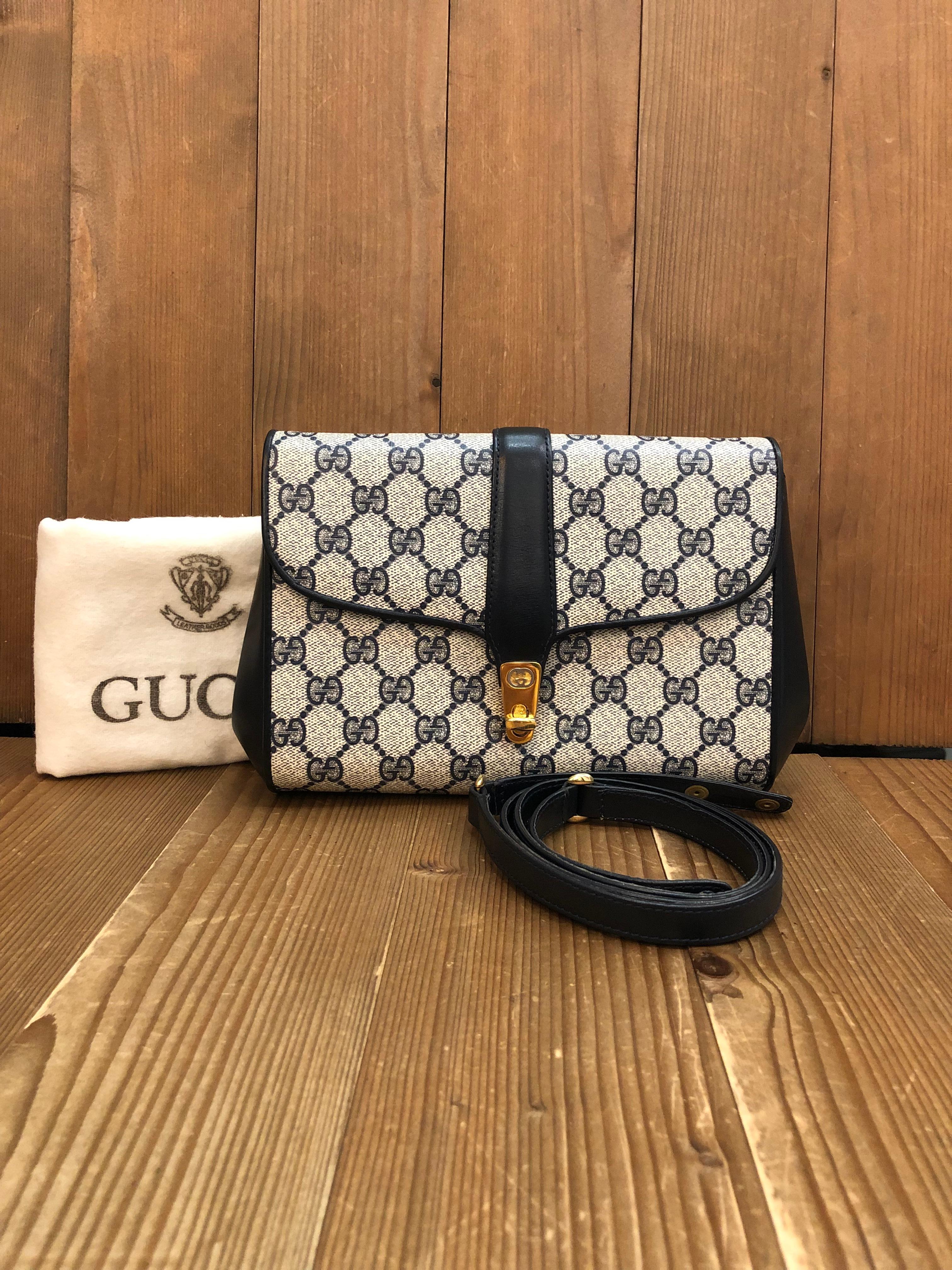 This Vintage GUCCI 2-way clutch shoulder bag is crafted of GG monogram canvas in navy trimmed with navy smooth leather featuring a gold toned turnlock and a silver toned GG logo. Front flap turnlock closure opens to a leather interior in navy