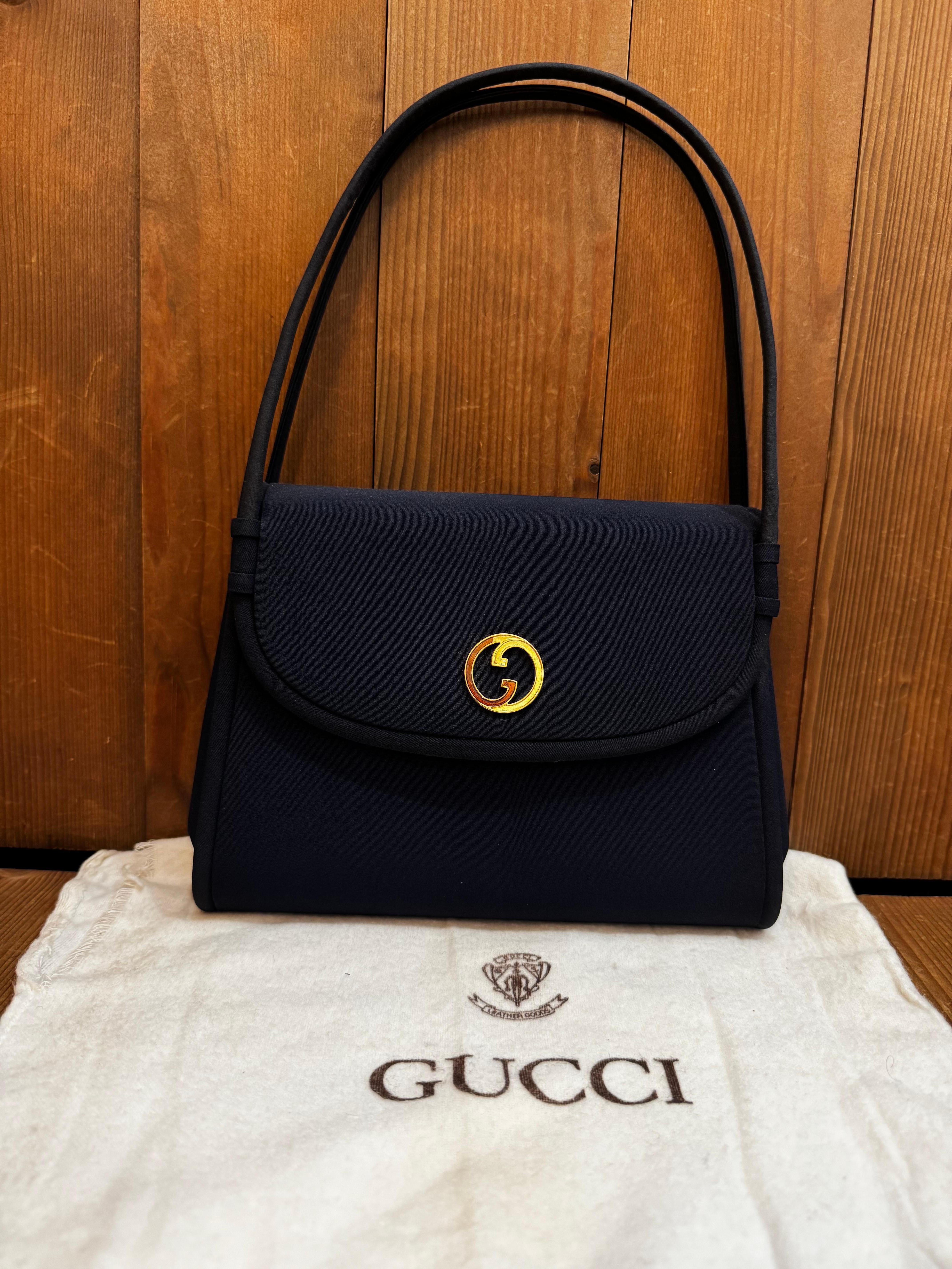 This vintage GUCCI small handbag is crafted of polyester fabric in navy featuring gold-toned hardware. Front flap magnatic snap closure opens to a navy satin interior featuring a patch pocket. This vintage Gucci is the perfect evening clutch for