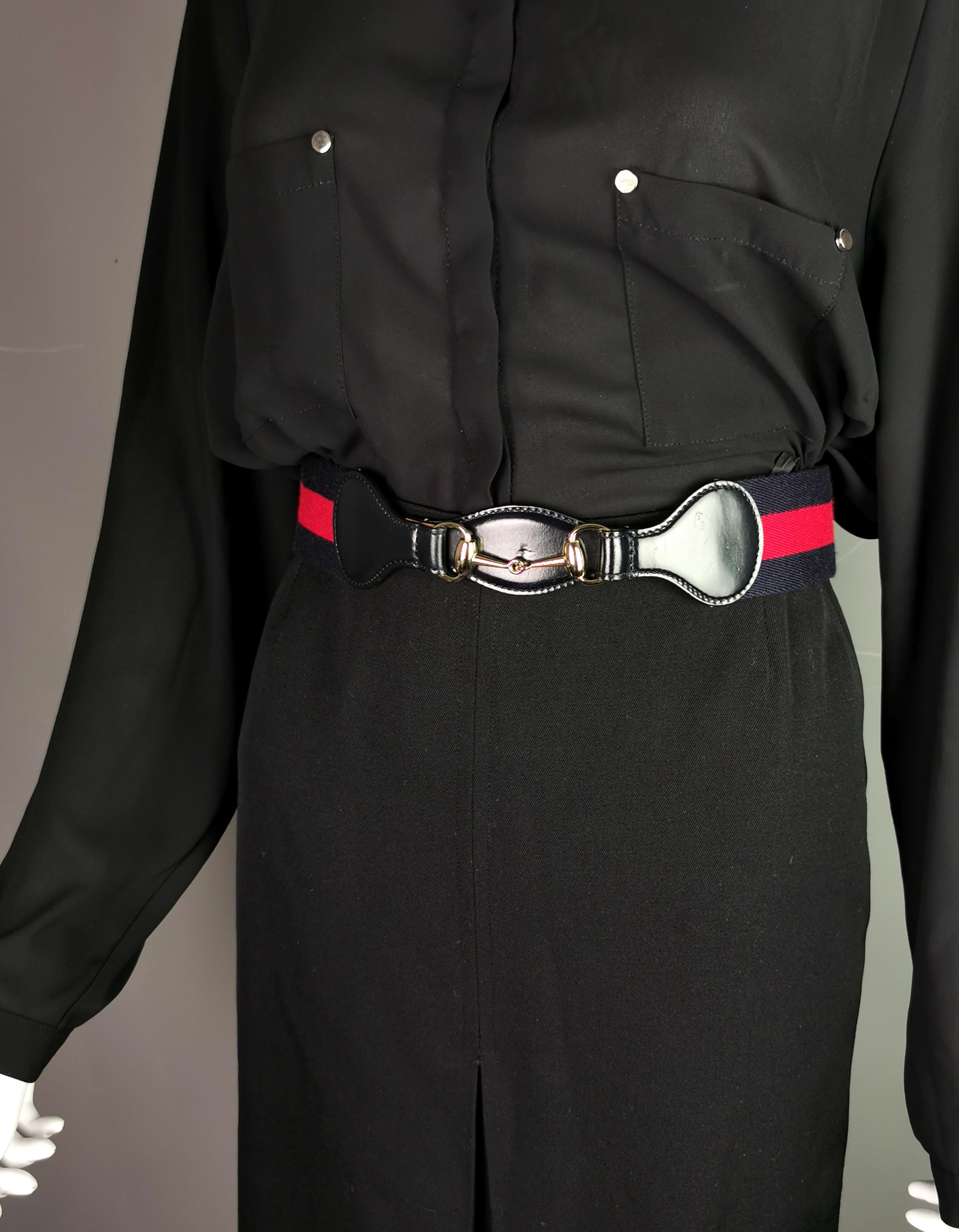 Das ultimative Must-Have-Accessoire ist dieser stilvolle Vintage-Gürtel von Gucci.

Der Gürtel ist aus klassisch gestreiftem Canvas mit einer glänzenden navyfarbenen Lederfront und Riemen sowie einem goldfarbenen Metall-Pferdekopf auf der