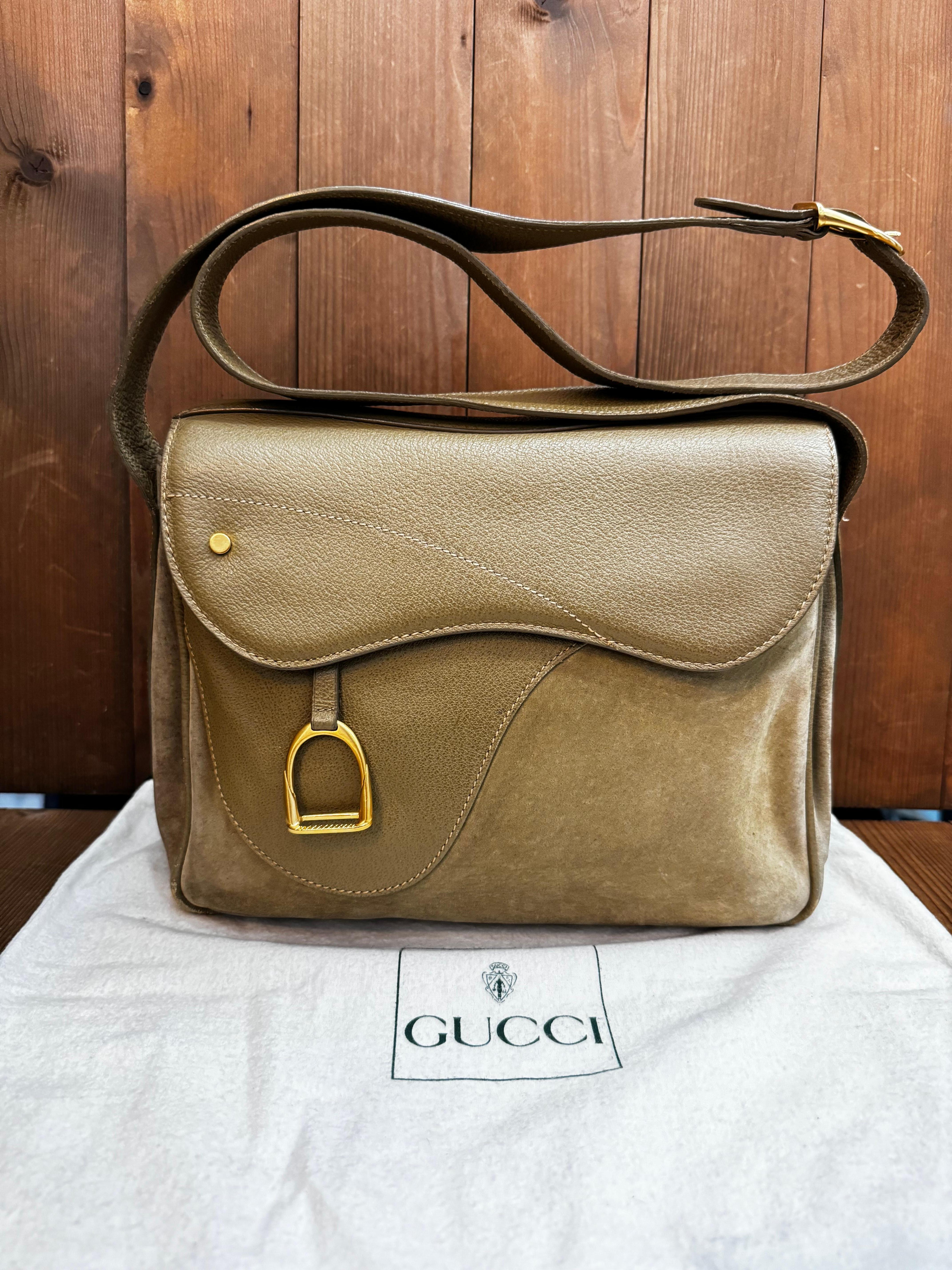 This vintage GUCCI saddle camera bag is crafted of nubuck and pigskin leather in khaki featuring matte gold toned hardware. Front flap double magnetic snap closure opens to a khaki diamanté jacquard interior featuring three compartments with a