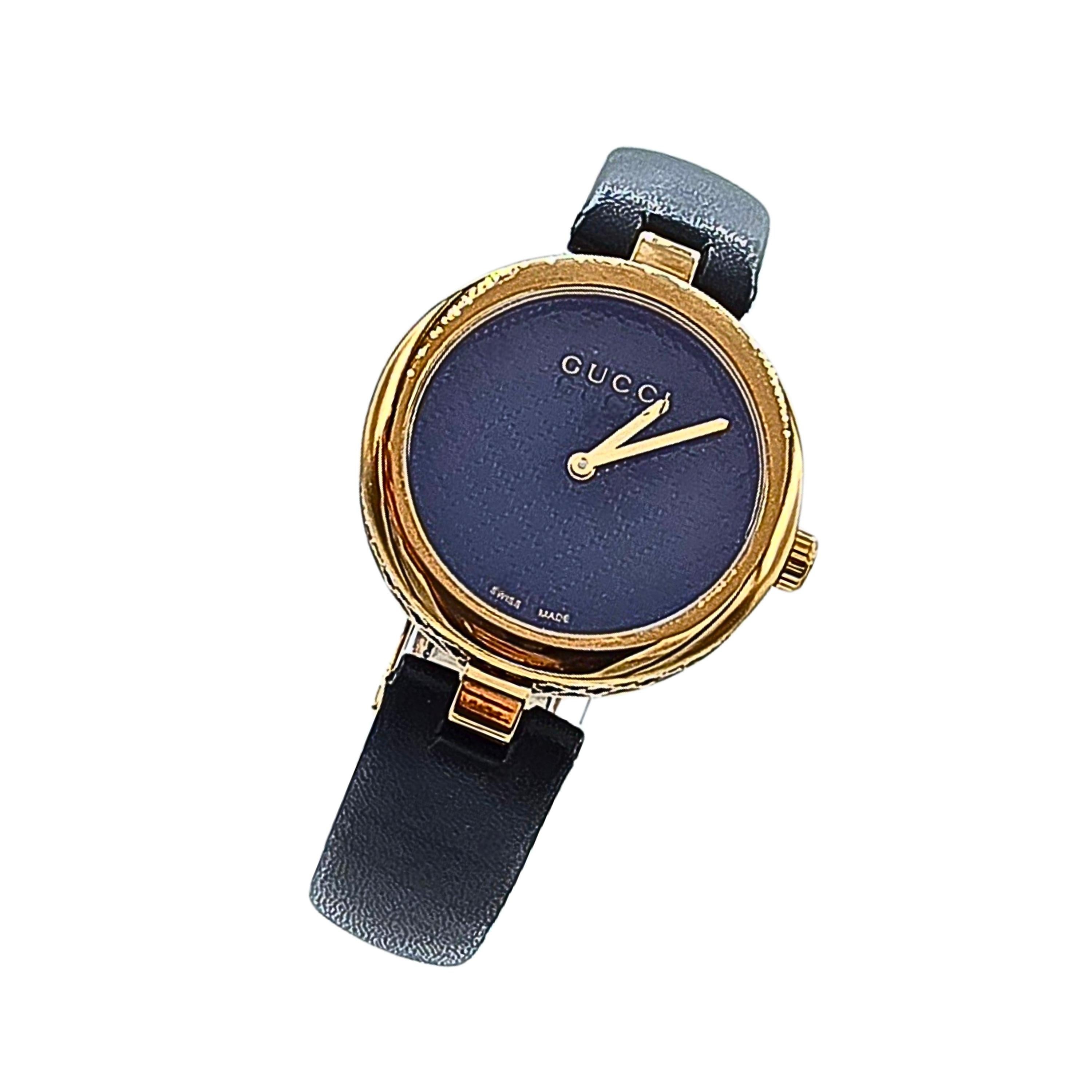 Se trata de un reloj Gucci Diamantissima usado.  Presenta la firma Gucci Diamante grabada en el lateral y la parte posterior de la caja.  El mismo motivo se presenta en la esfera negra (cara) del reloj, dándole un efecto de tejido estampado/grabado.