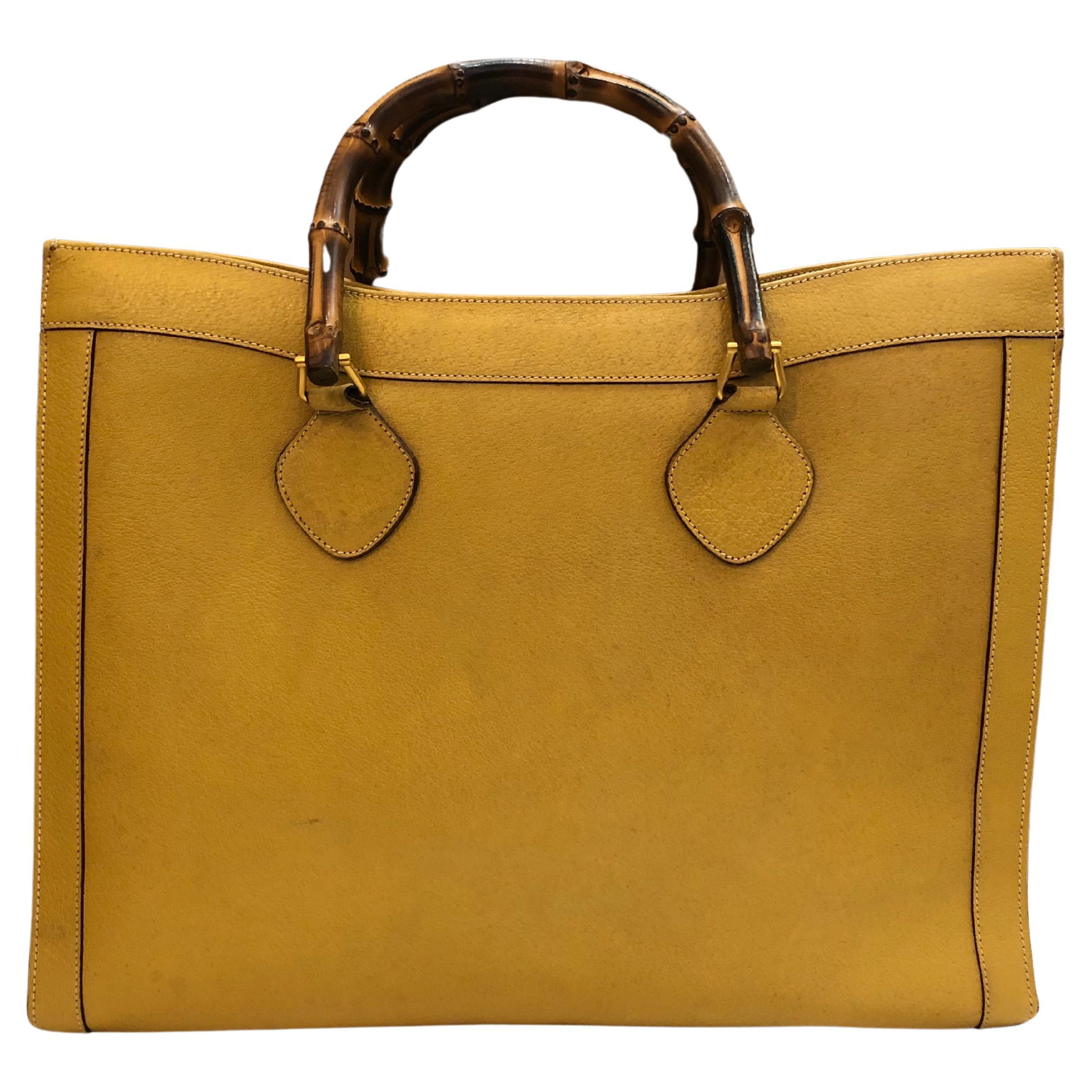 This large vintage Gucci Diana bamboo tote bag is crafted of pigskin leather in yellow featuring matte gold-toned hardware and sturdy bamboo handles. Wide top opens to one single spacious compartment with original beige leather interior featuring a