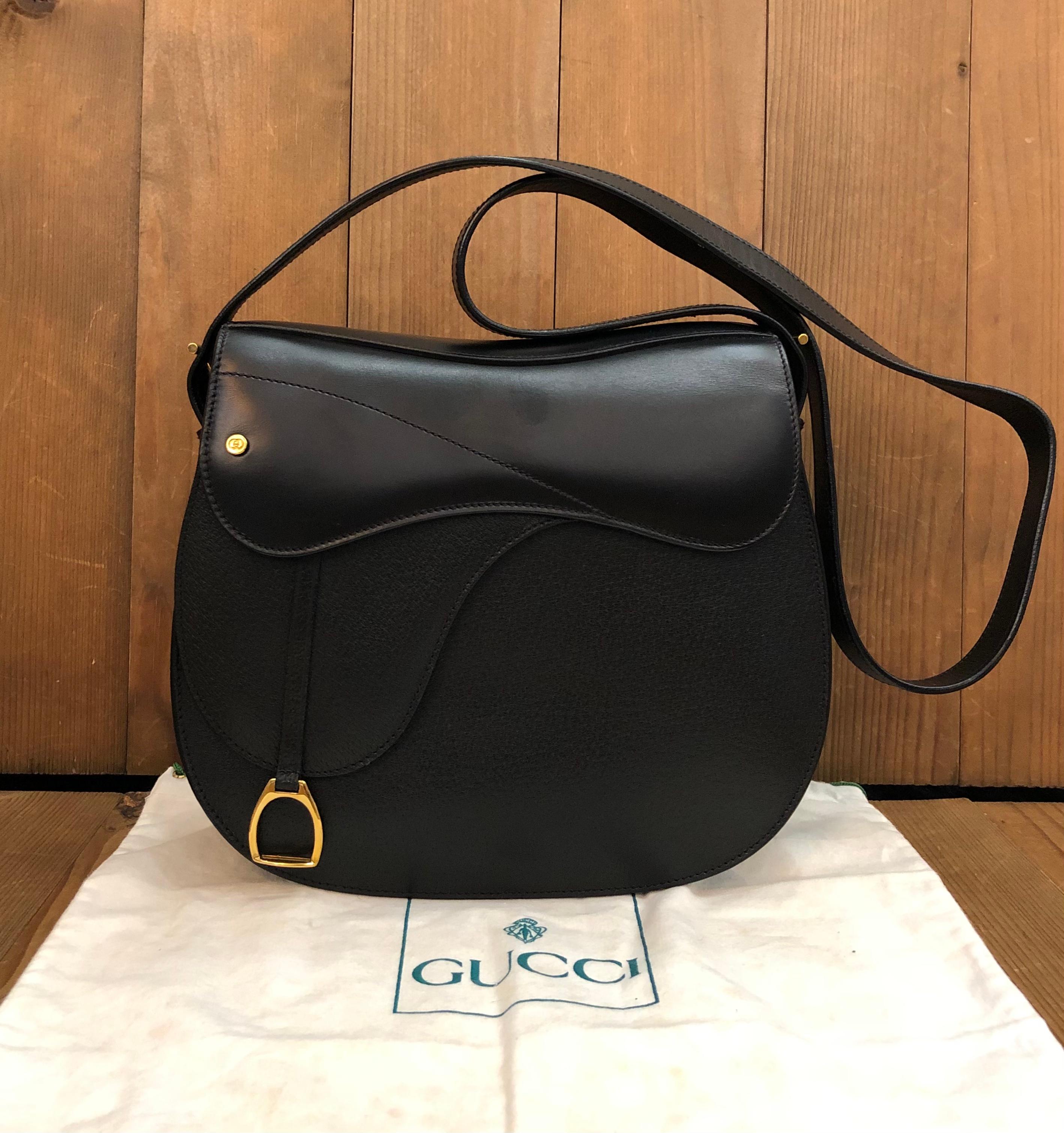 This vintage GUCCI saddle bag is crafted of smooth calfskin and pigskin leather in black featuring gold toned hardware. Front magnetic snap closure opens to a black leather interior featuring a zippered pocket. Made in Italy. Measures approximately