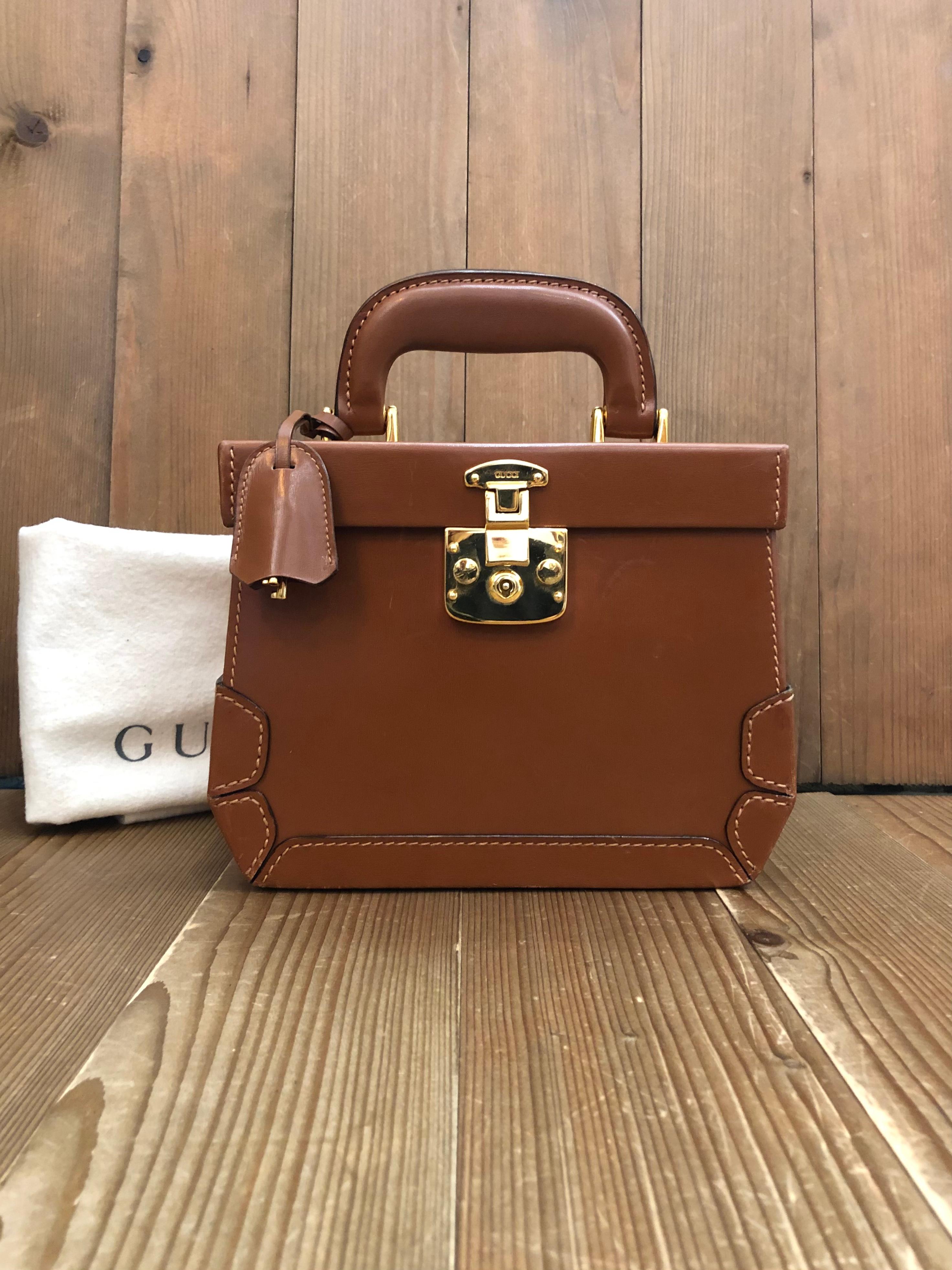 This vintage GUCCI vanity trunk case is crafted of smooth calfskin leather in brown featuring gold toned hardware. Front push-lock closure opens to a smooth leather interior in brown  featuring a mirror and a zippered pocket. Made in Italy. Measures