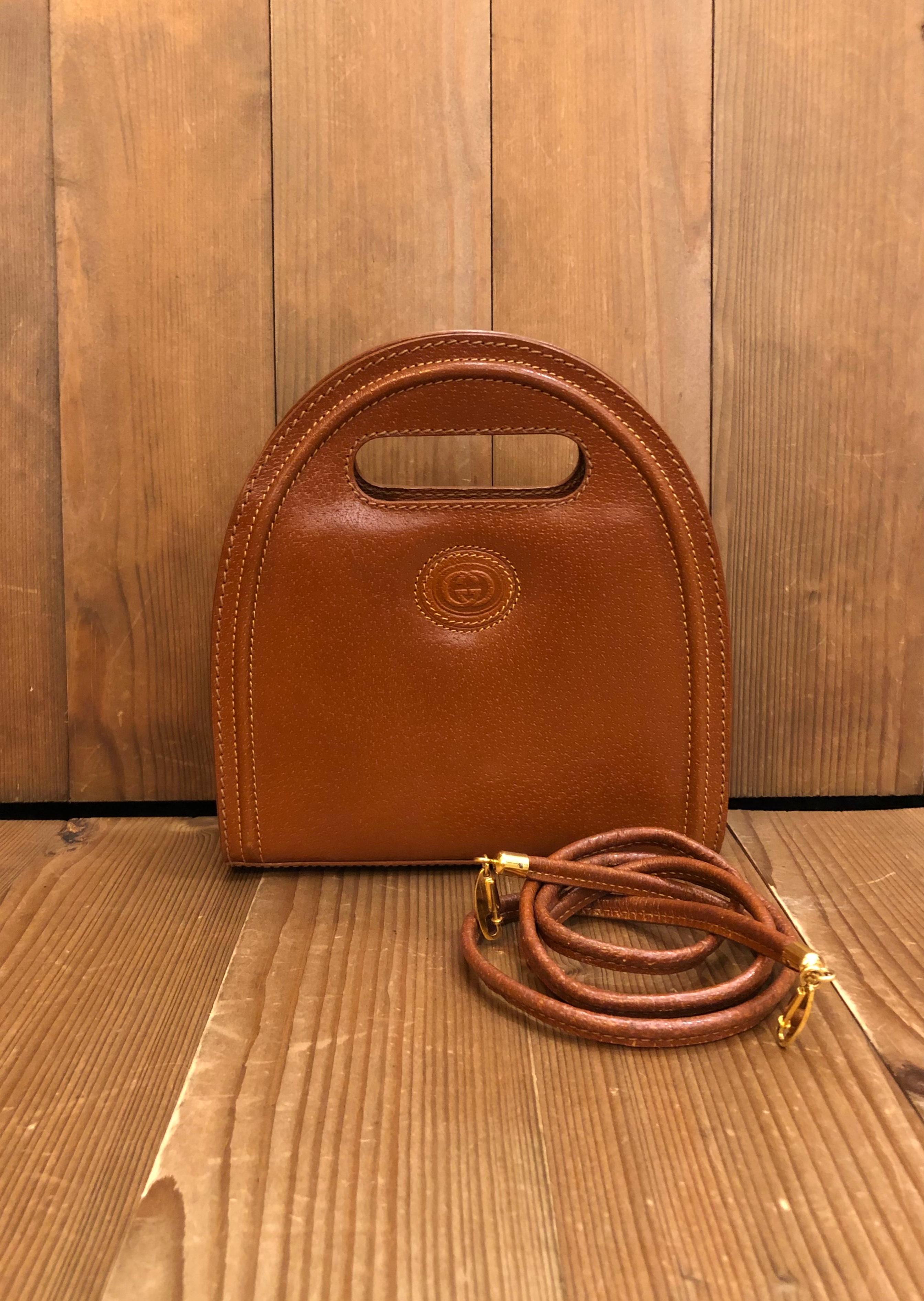 This vintage GUCCI mini book tote is crafted of pigskin leather in caramel color featuring a detachable crossbody strap of the same leather. Magnetic snap closure opens to an all suede interior with one zippered pocket. Made in Italy. Measures