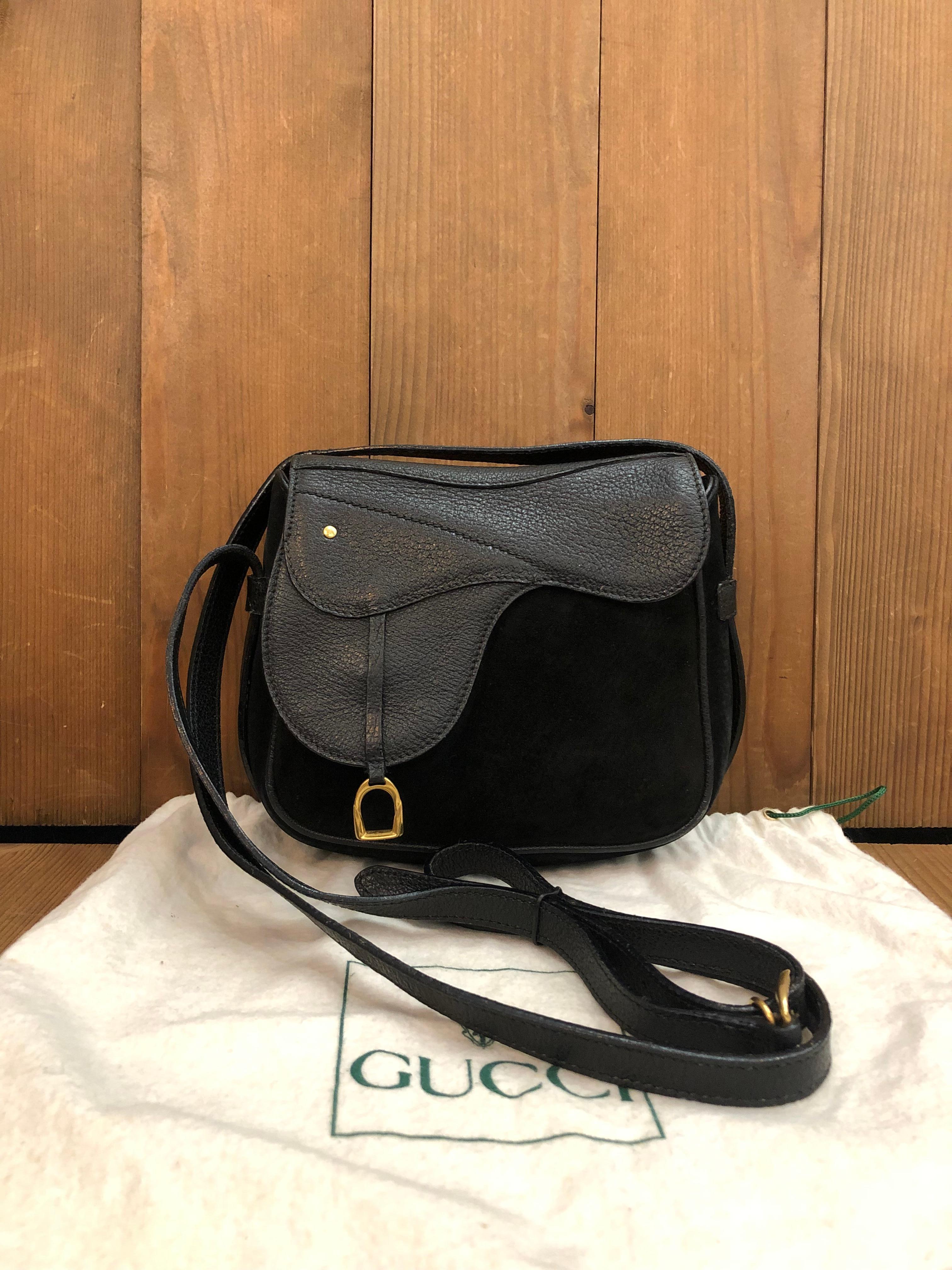 This vintage GUCCI mini saddle crossbody bag is crafted of pigskin and nubuck leather in black featuring gold toned hardware. This bag also features two leather loops at the back for securing it on your belt. Front magnetic snap closure opens to a