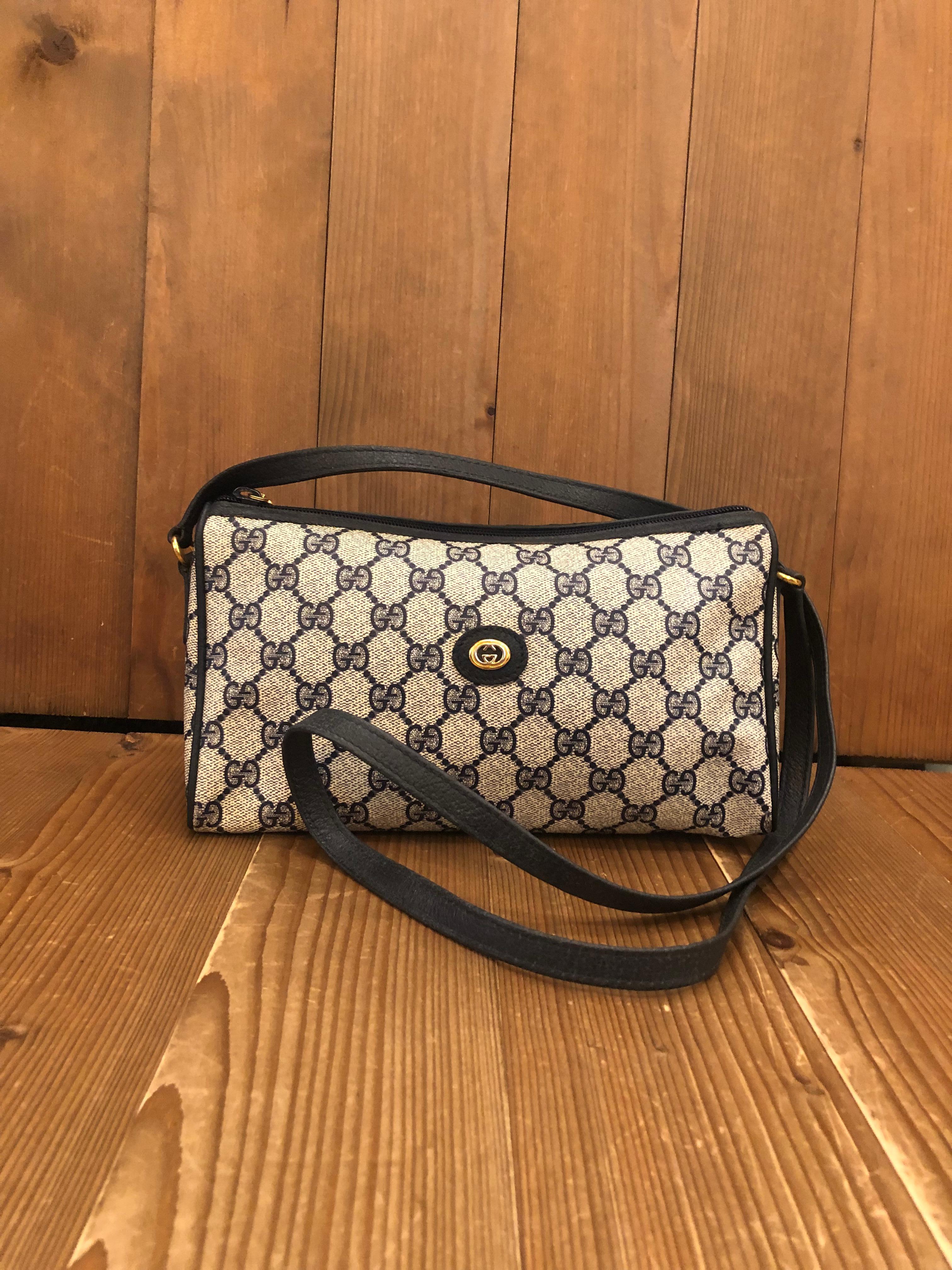 This vintage GUCCI triangle crossbody bag is crafted of monogram canvas and leather in navy. Zipper top closure opens to a coated interior in navy featuring a zippered pocket. Made in Italy. Measures approximately 9.5 x 5 x 4.5 Drop 21