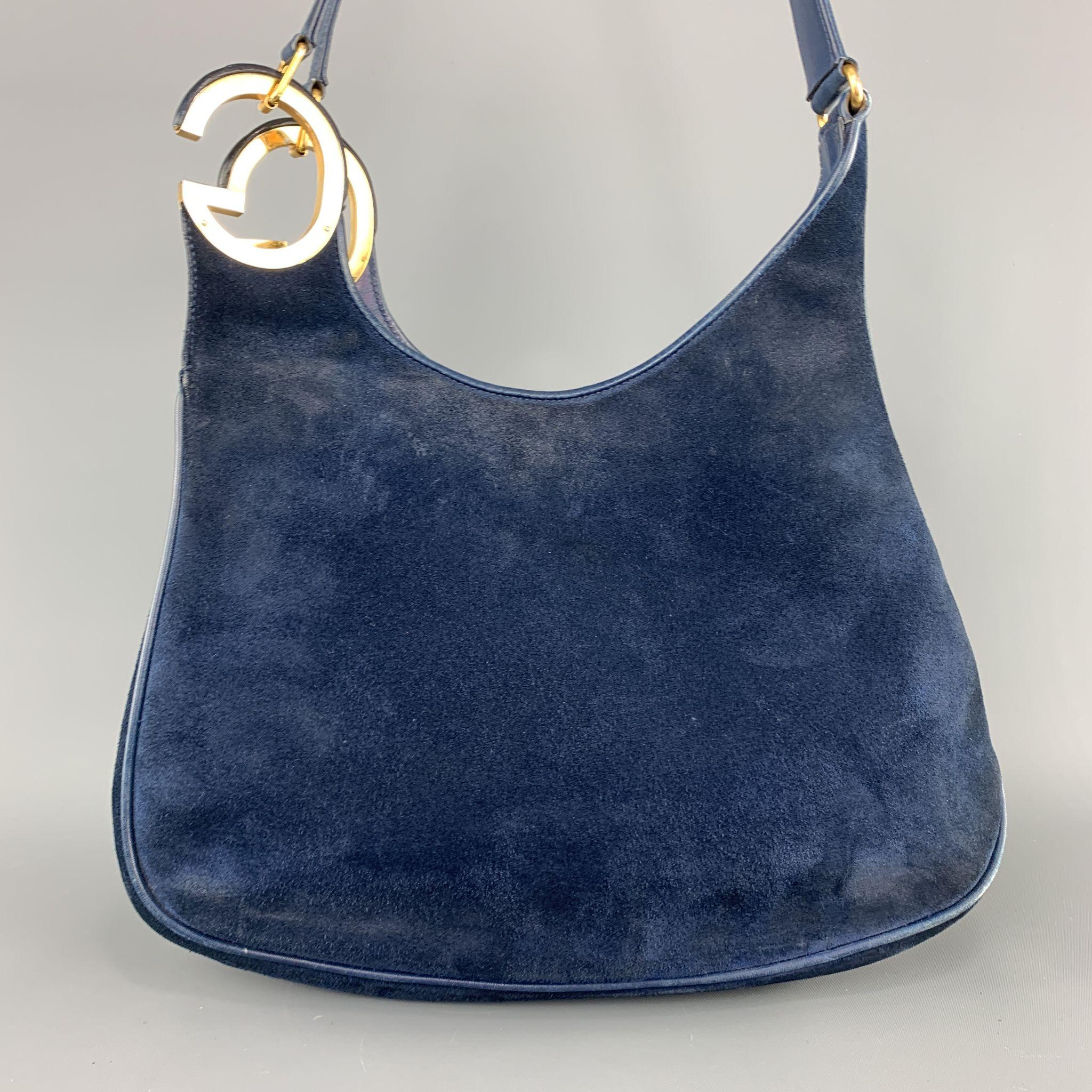 Vintage 1970's-1980's GUCCI shoulder bag comes in navy blue suede with leather piping, yellow gold tone metal hardware, and double oversized GG metal accent. Wear and aging throughout leather and suede. As-is. Made in Italy.

Good Pre-Owned
