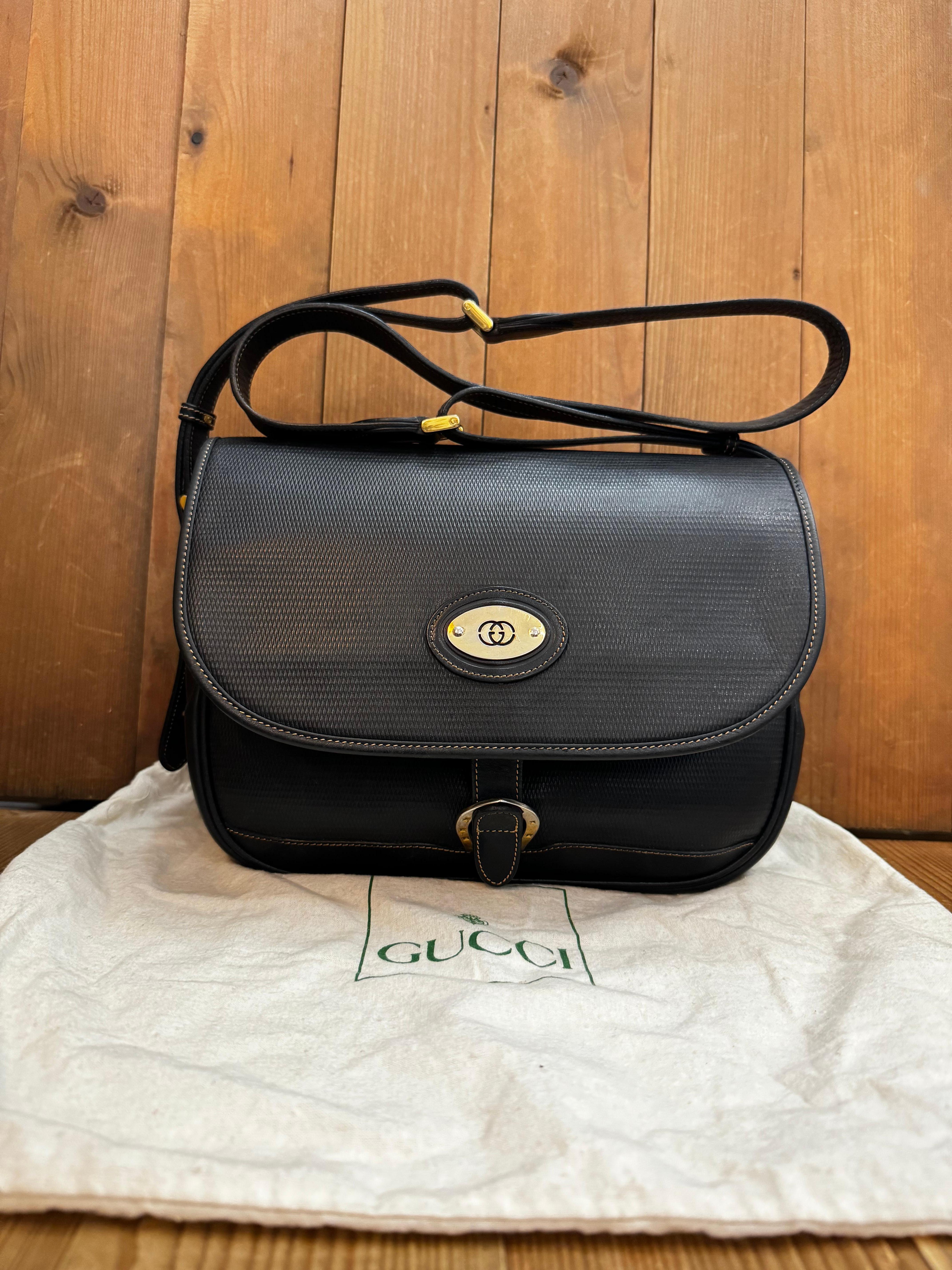 This vintage GUCCI camera crossbody bag is crafted of textured calfskin leather in black with equestrian accent. Front flap closure opens to a front zippered pocket and a main compartment lined with suede leather featuring a zippered pocket.