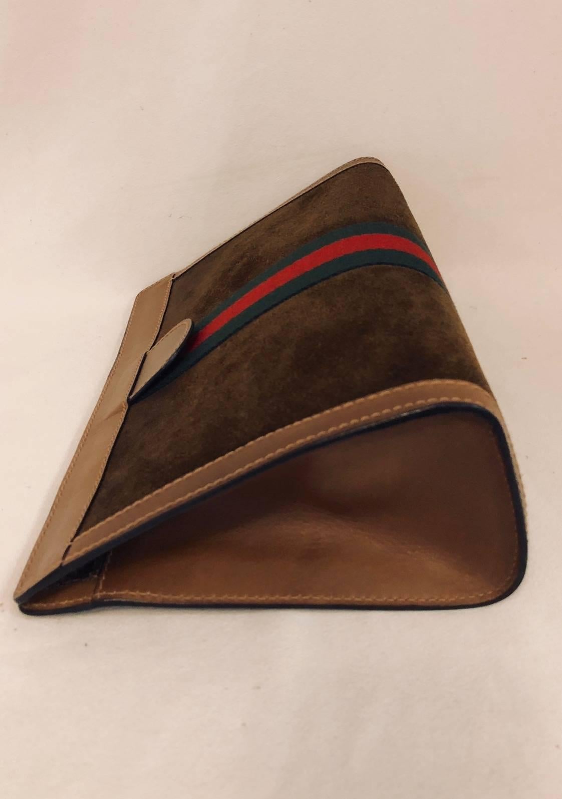 Substantial enough to carry as a clutch, this vintage brown suede cosmetic bag is a must for any connoisseur of Gucci leather goods in general and handbags in particular!  Features triangular shape, tan leather trim and sides, signature green and