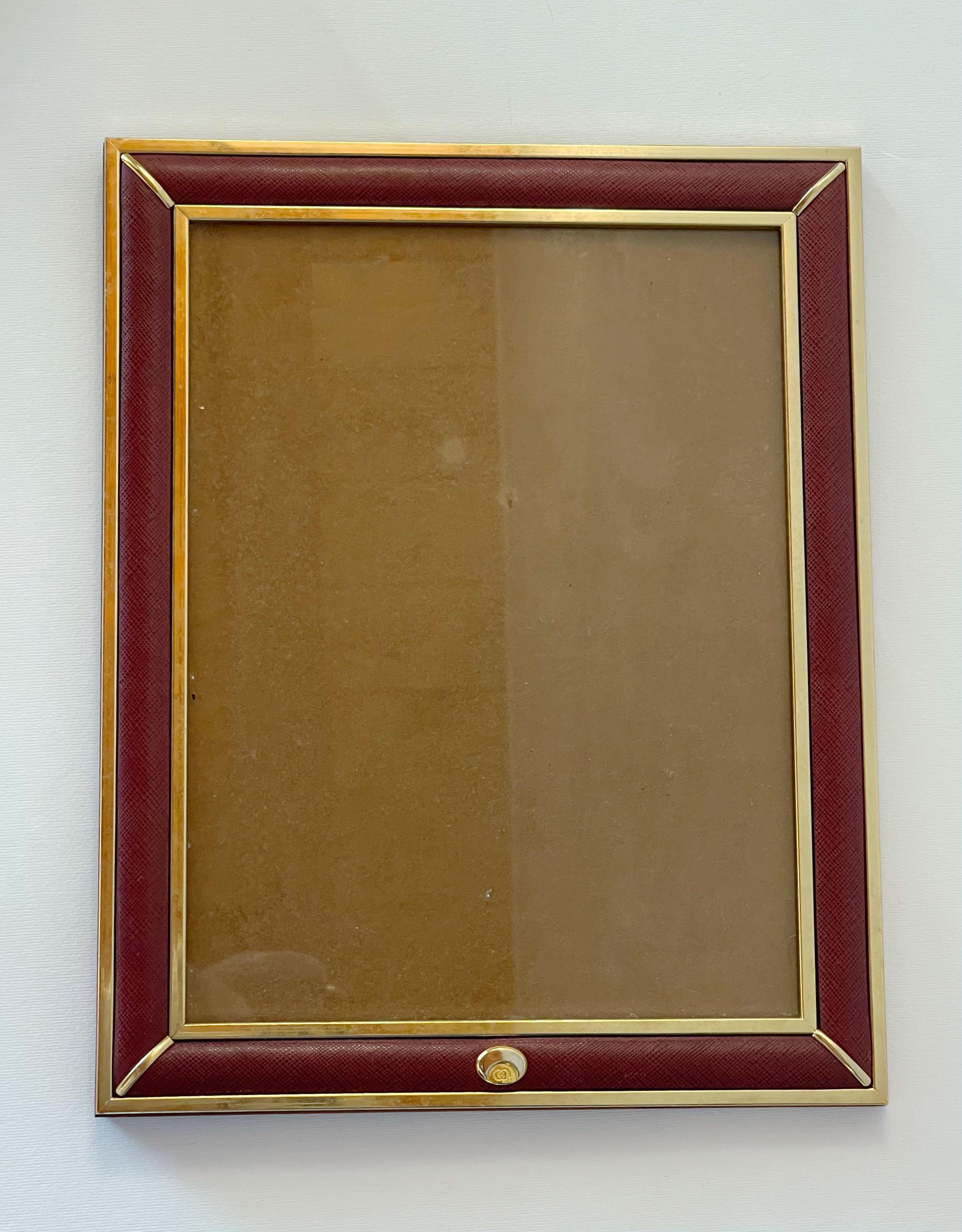 Cornice rettangolare vintage di Gucci con pelle rossa, bordo dorato, retro e cavalletto in legno / Made in Italy circa anni '60
Il logo GG è inciso sul davanti e la scritta 