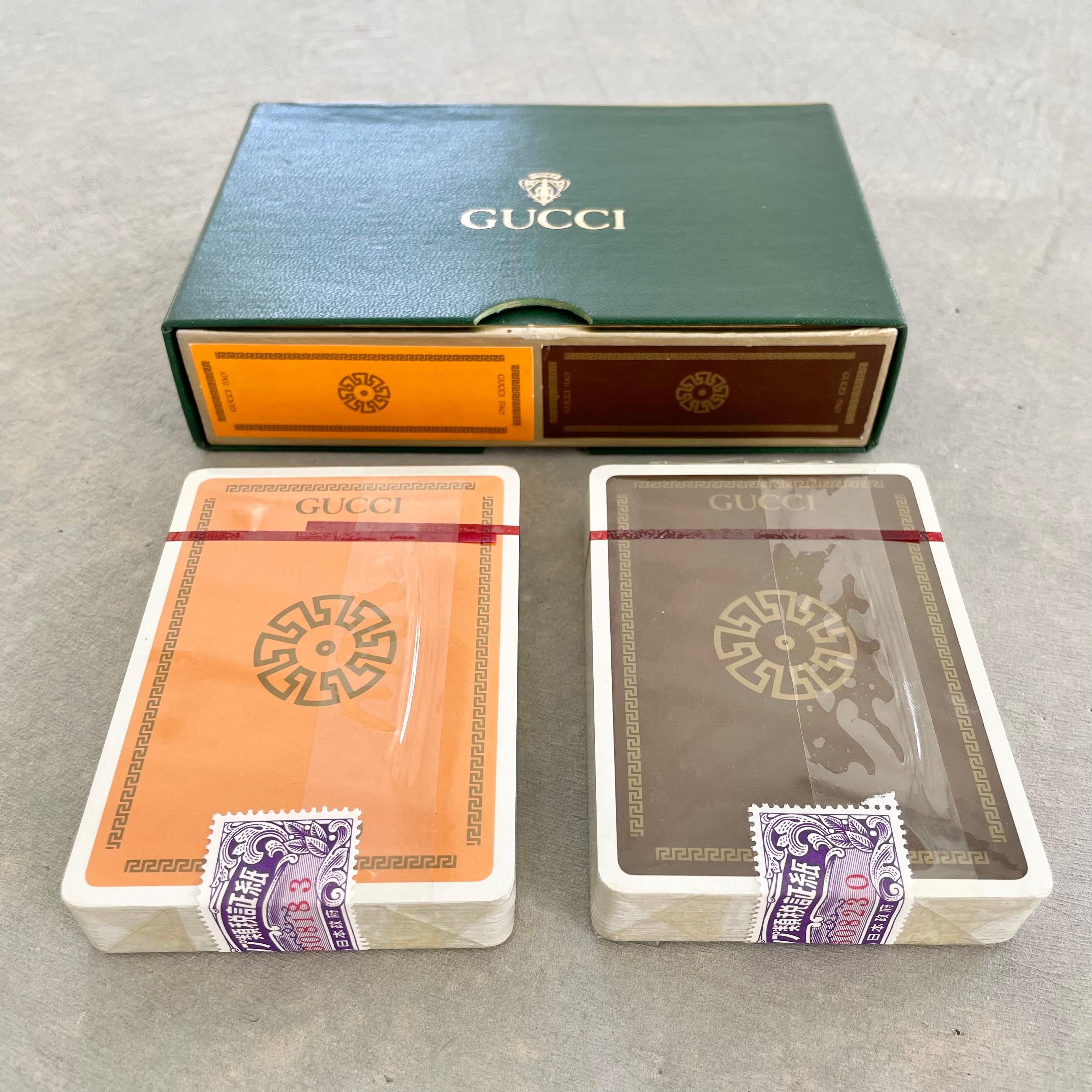 Gucci playing cards in the original box and original wrapping. Made in Italy, circa 1970s. Both sets are sealed and un-used with serial numbers on seal. Gucci knight logo stamped on the shell of the green leather case. There is a brown deck and a