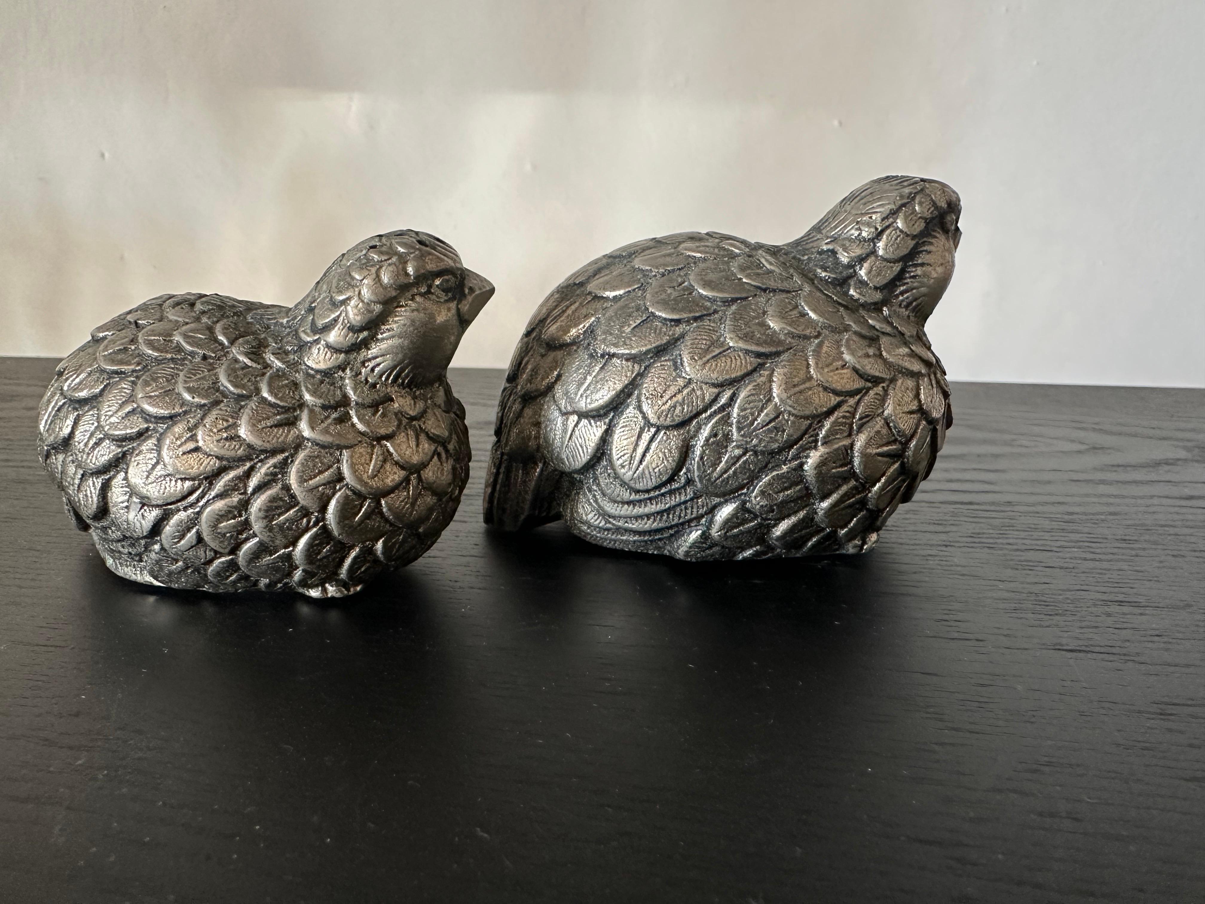 This unique and collectible pair of salt and pepper shakers from Gucci, crafted in Italy around 1970, showcases a lifelike quail design in silver-toned metal. Featuring a charmingly naturalistic form, each quail is fully three-dimensional, with one