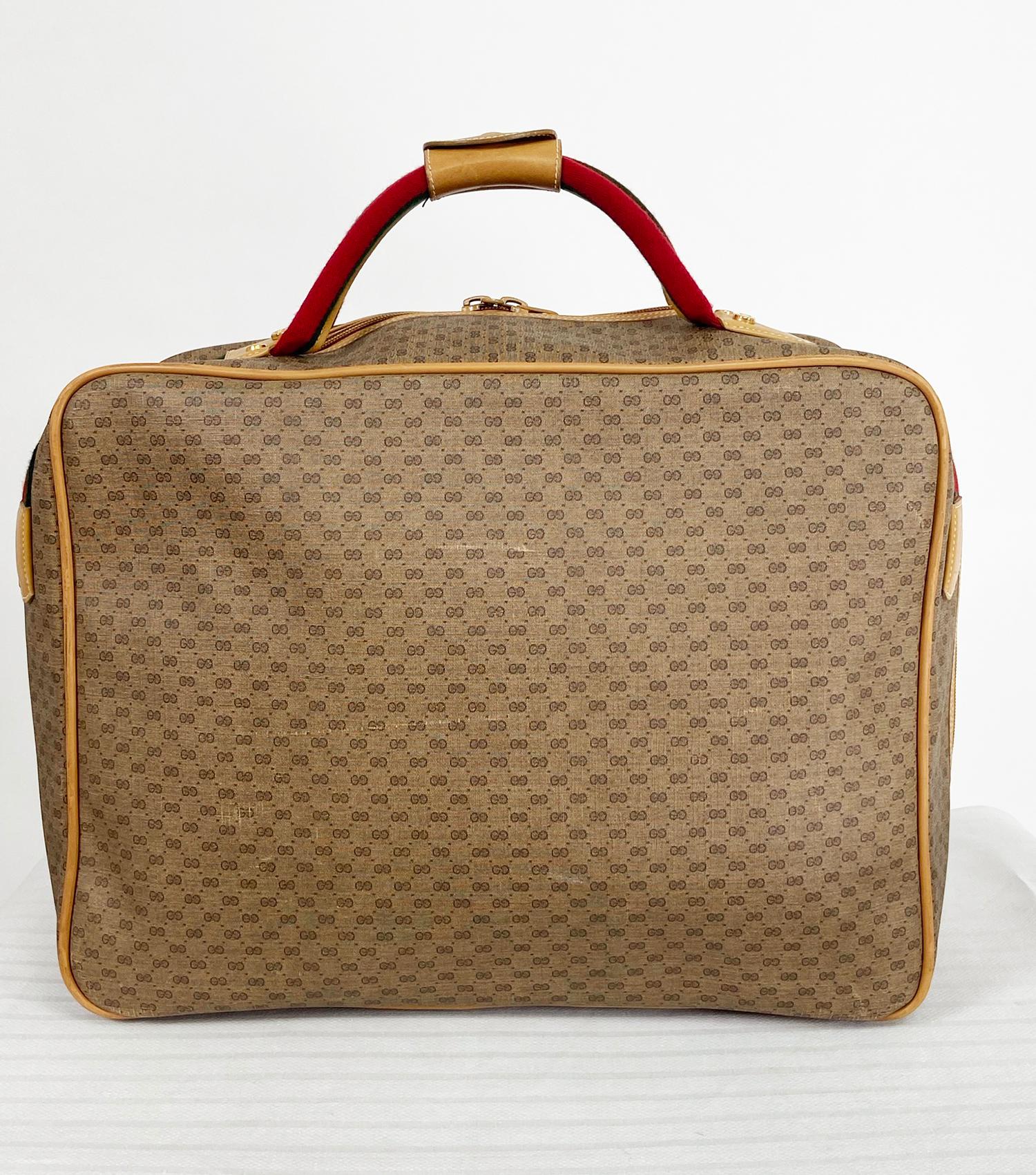 Vintage Gucci monogram vinyl canvas, carry on suit case. Double red & green web handles in red & green, tan leather trim hold close with gold snap. The bag is perfect for carry on. Unzips from front center to back sides. Interior is canvas and clean
