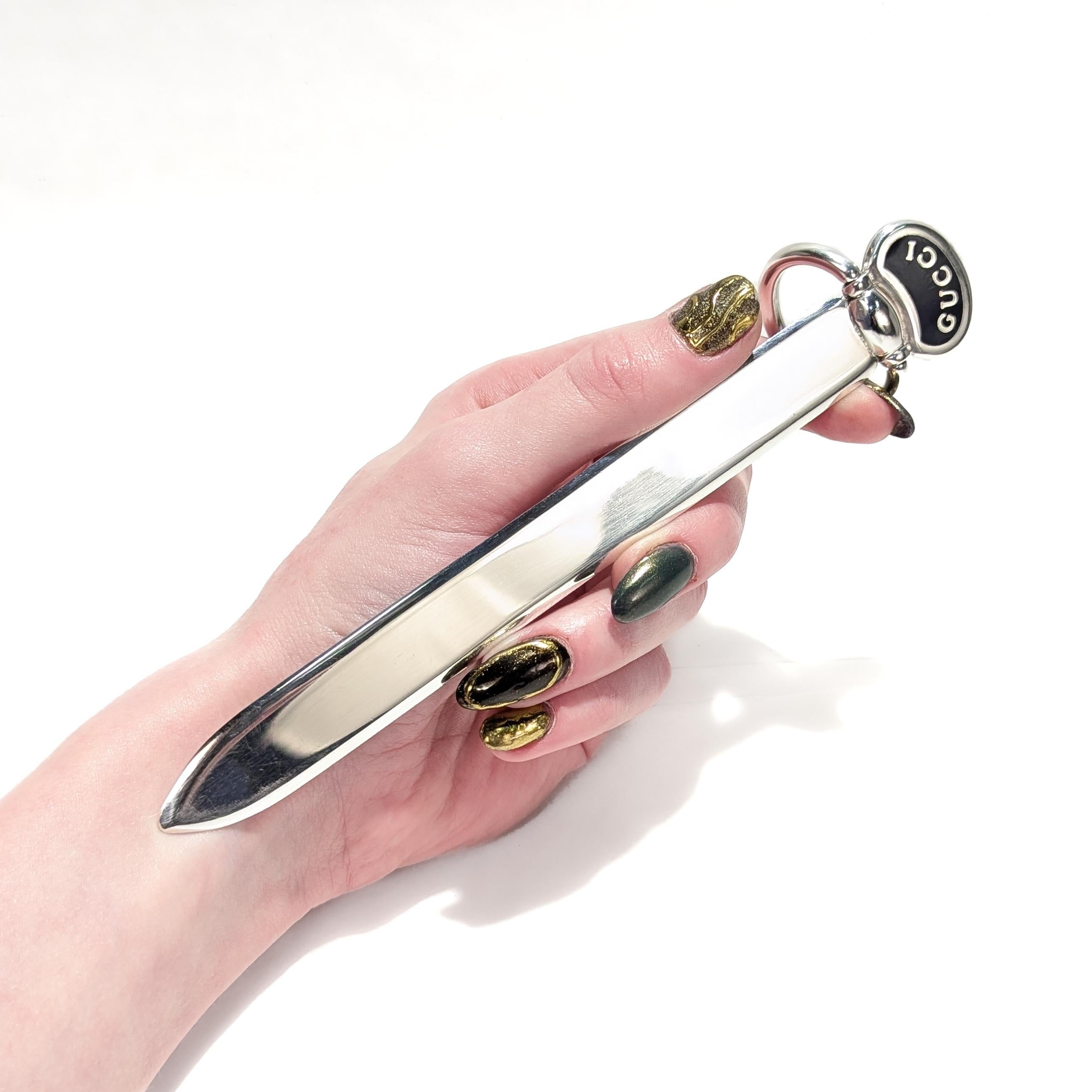 A fine vintage Italian designer letter opener.

In sterling plate.

By Gucci.

With a ring shaped handle surrounding a bean shaped device that reads 'GUCCI' on a black enamel band.

Simply a wonderful letter opener from Gucci!

Date:
20th