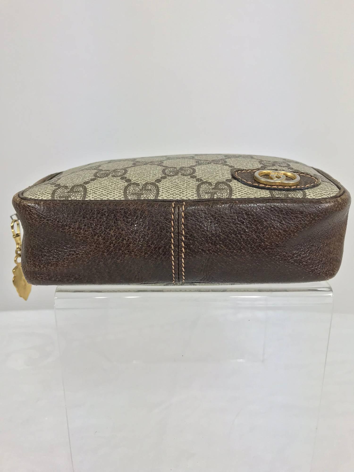Vintage Gucci small leather and monogram vinyl cosmetic bag...Oval leather applique with metal intertwined G's at the front, the bag is pigskin leather at the sides, top and bottom...Lined in brown vinyl...Some wear but basically in very good usable