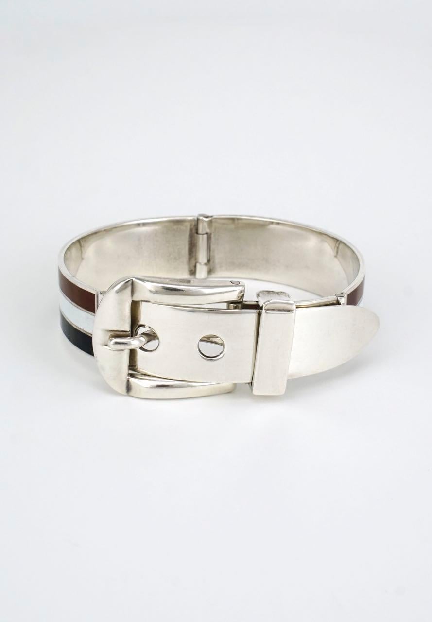 An iconic Gucci sterling silver hinged bracelet of two panels of three stripes with a central white stripe bordered by brown and black stripes with a hinged working buckle and three hole hinged belt tip - marked for Gucci Italy, sterling and a pre