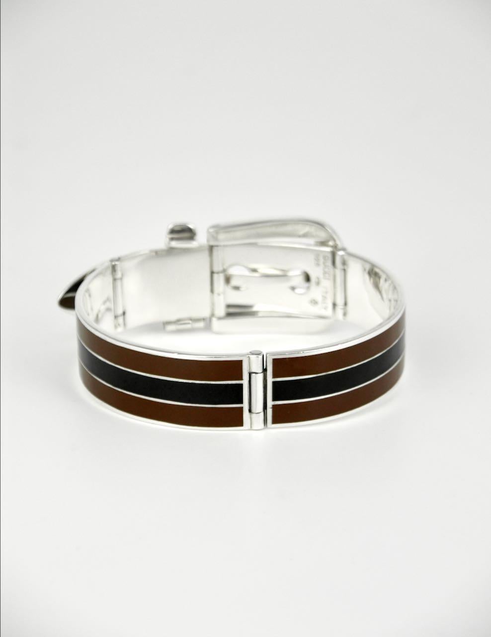 An iconic Gucci solid silver black and brown enamel belt bracelet consisting of two hinged panels each decorated with three stripes with a central black stripe bordered by brown stripes with a hinged working buckle and three hole hinged belt tip -