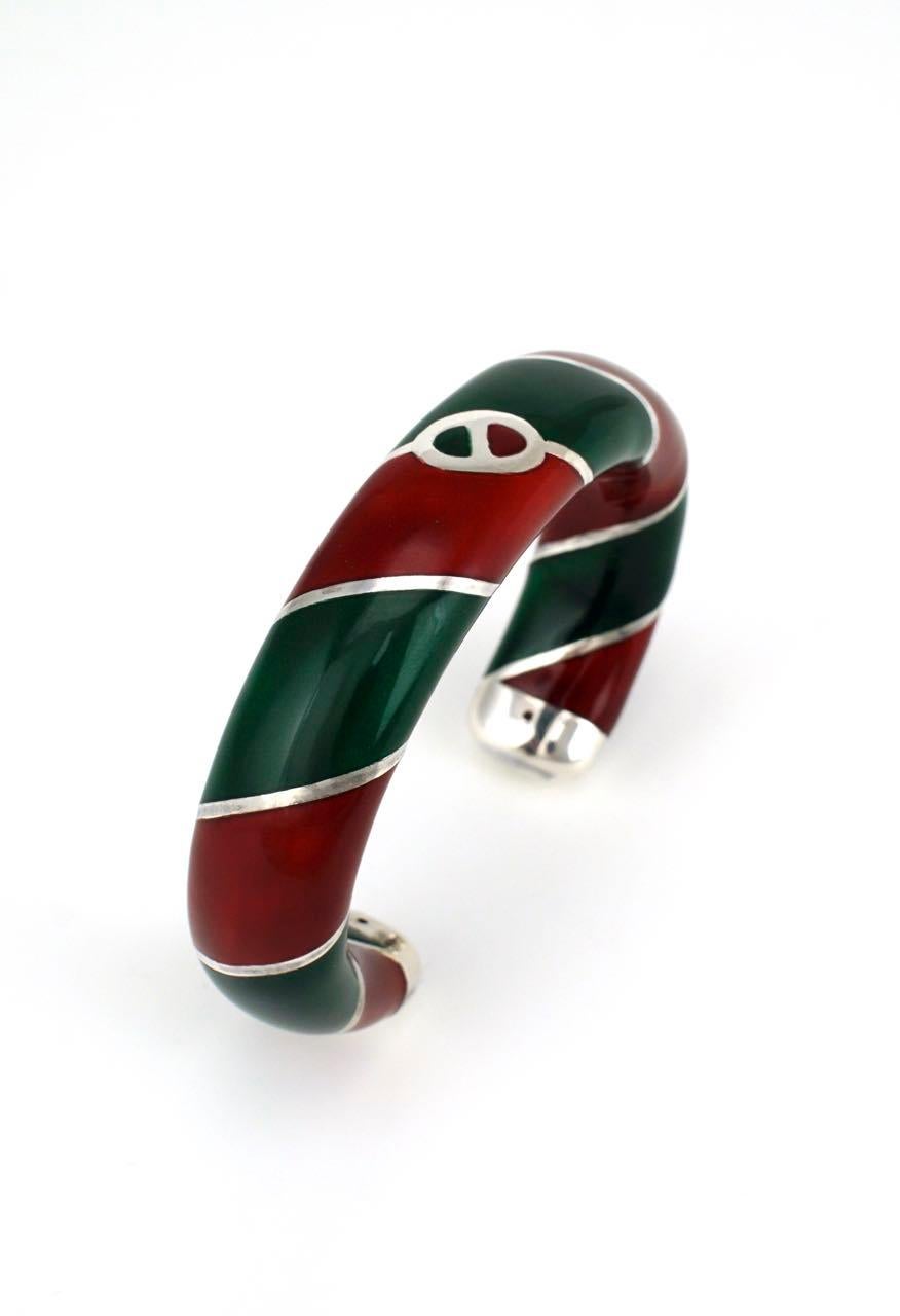 A striking Sterling silver hollow tubular cuff with wrapped stripes of red and green enamel with a central Gucci link logo.  This Designer bangle in the iconic Gucci colours is presented in its original Gucci green fabric presentation box - marked