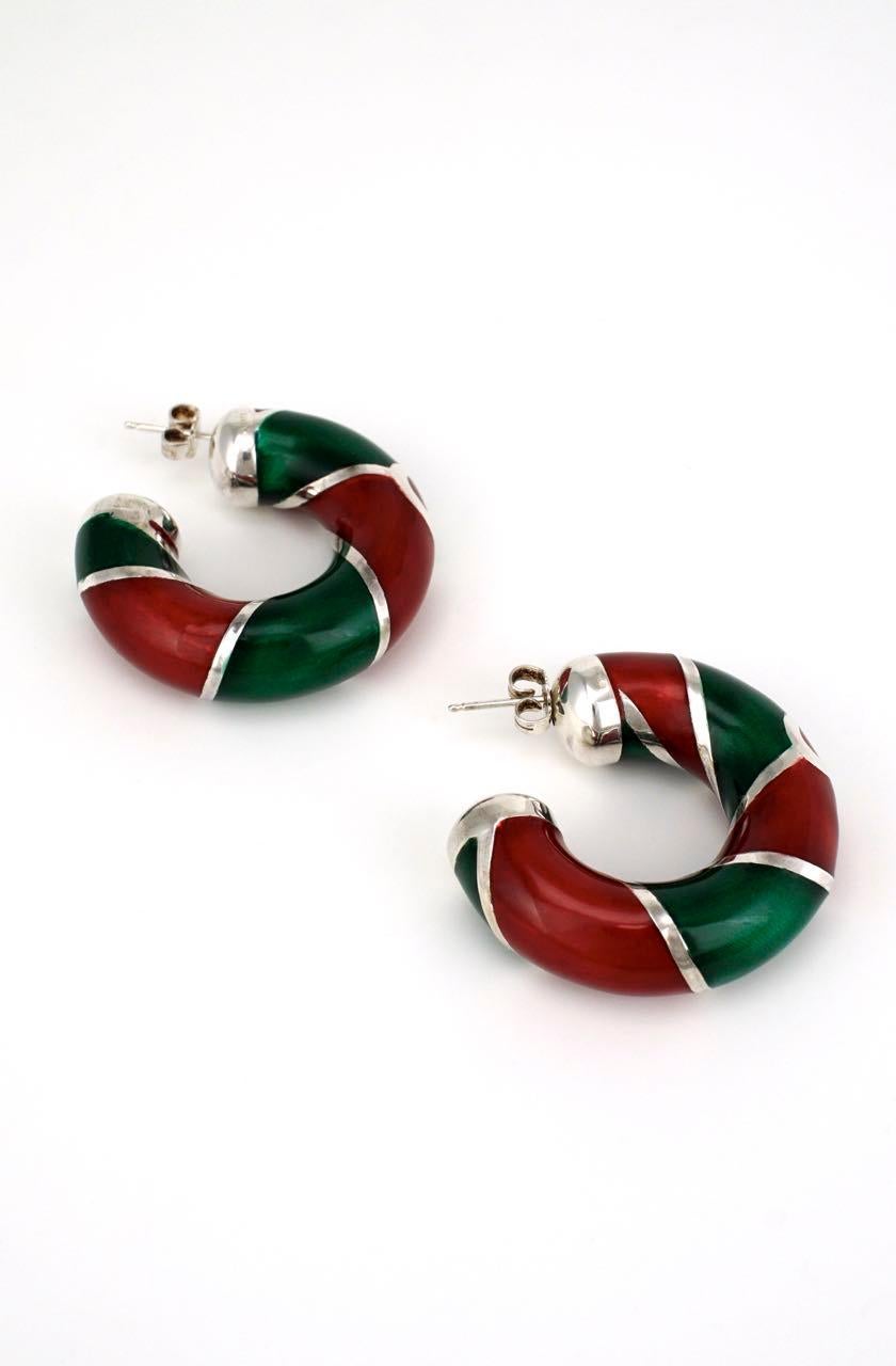 Each Designer earring of a hollow tubular solid silver 3/4 hoop shape with wrapped stripes of red and green enamel with a central Gucci link logo and a post fitting for pierced ears. Of great scale and in the Iconic Gucci colours, these earrings are