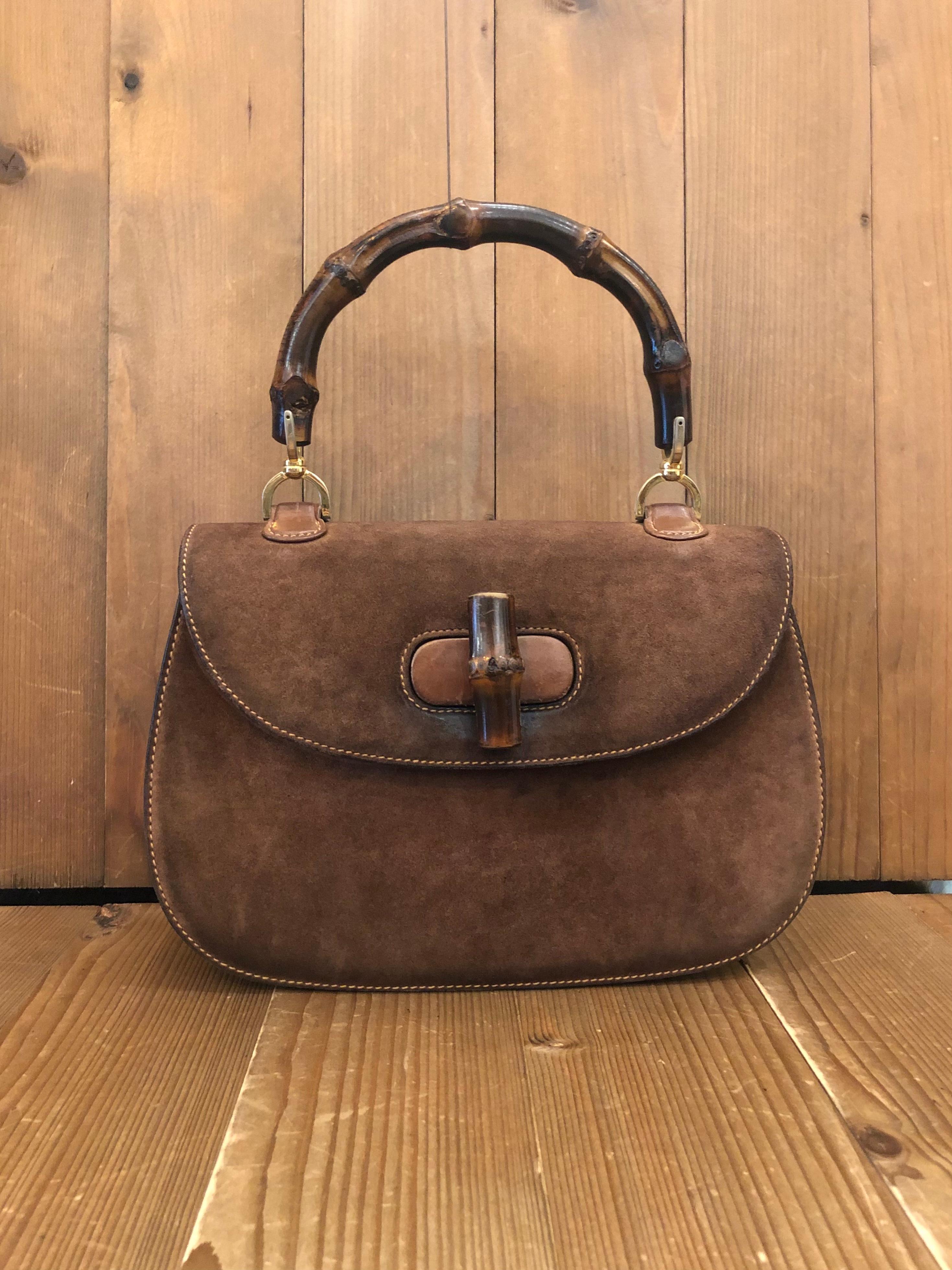 This vintage GUCCI bamboo top handle handbag is crafted of nu buck leather in brown featuring gold toned hardware and a signature Gucci bamboo handle. Front flap bamboo turnlock closure opens to a beige leather interior featuring zippered and patch
