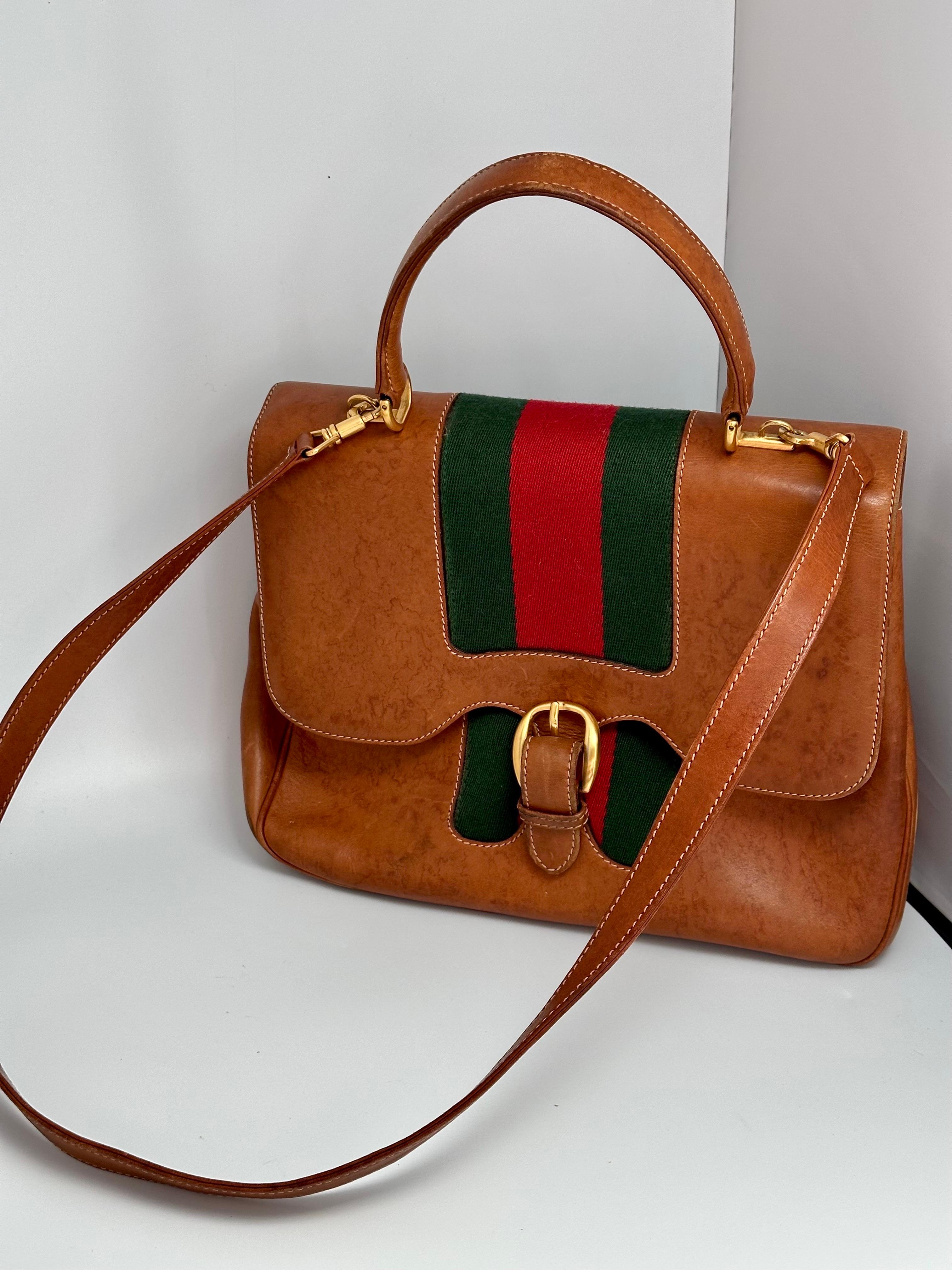 Gucci · Genuine Leather
Vintage Gucci handbag in tan leather with signature green and red fabric accent stripe.
 Inside is also Suede  lined. 
Leather has some dark patina or spots , please look at the pictures 
All Golden Hardware is in great