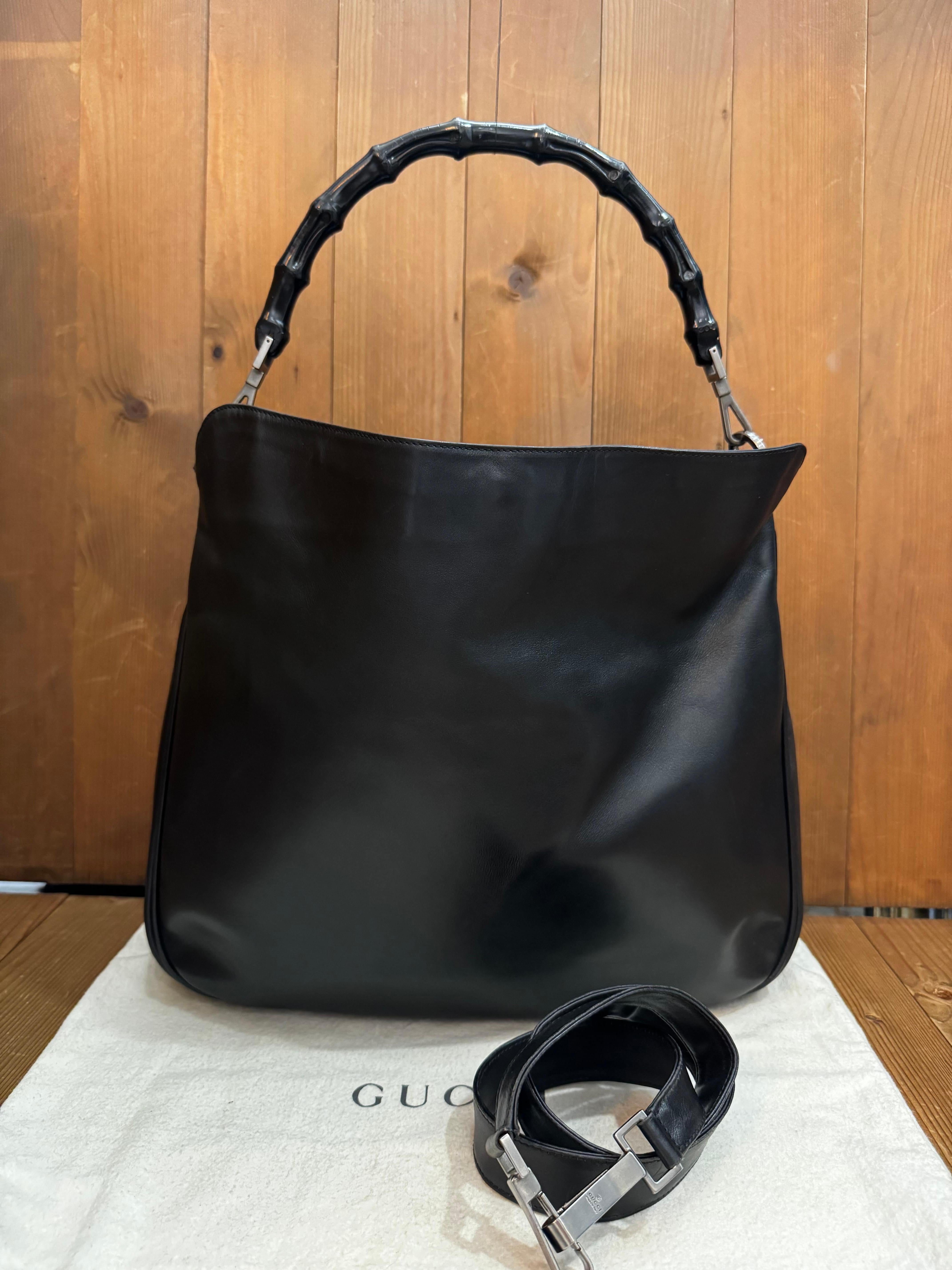 Este bolso cruzado vintage GUCCI de doble asa está fabricado en piel de becerro lisa de color negro, con herrajes cromados negros y asa de bambú lacada en negro. El cierre magnético superior se abre a un interior de jacquard negro Gucci con un
