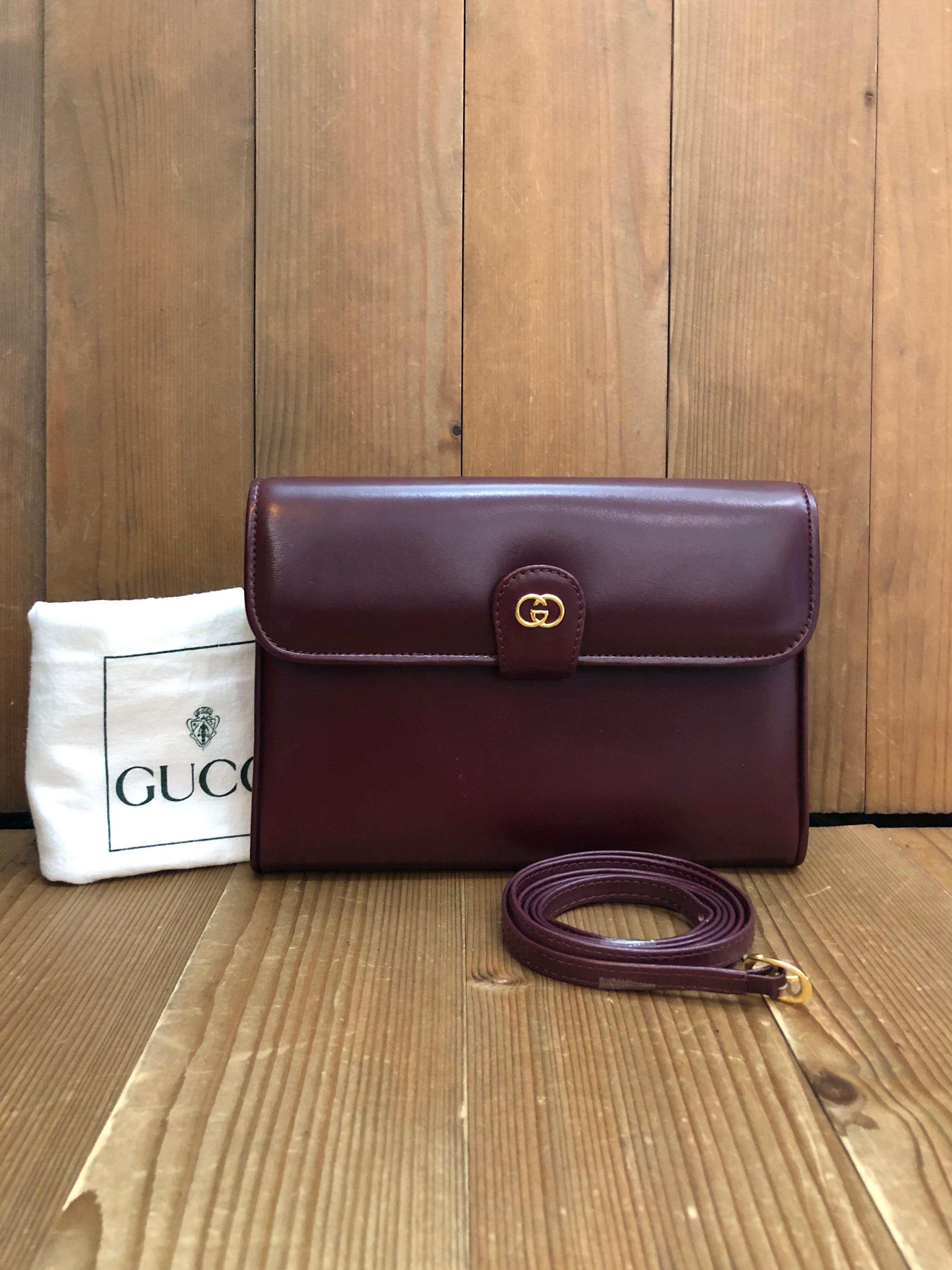 This vintage GUCCI two-way clutch crossbody bag is crafted of smooth calfskin leather in burgundy featuring gold toned hardware. Front flap GG snap closure opens to a luxurious nubuck leather interior featuring two main compartments and