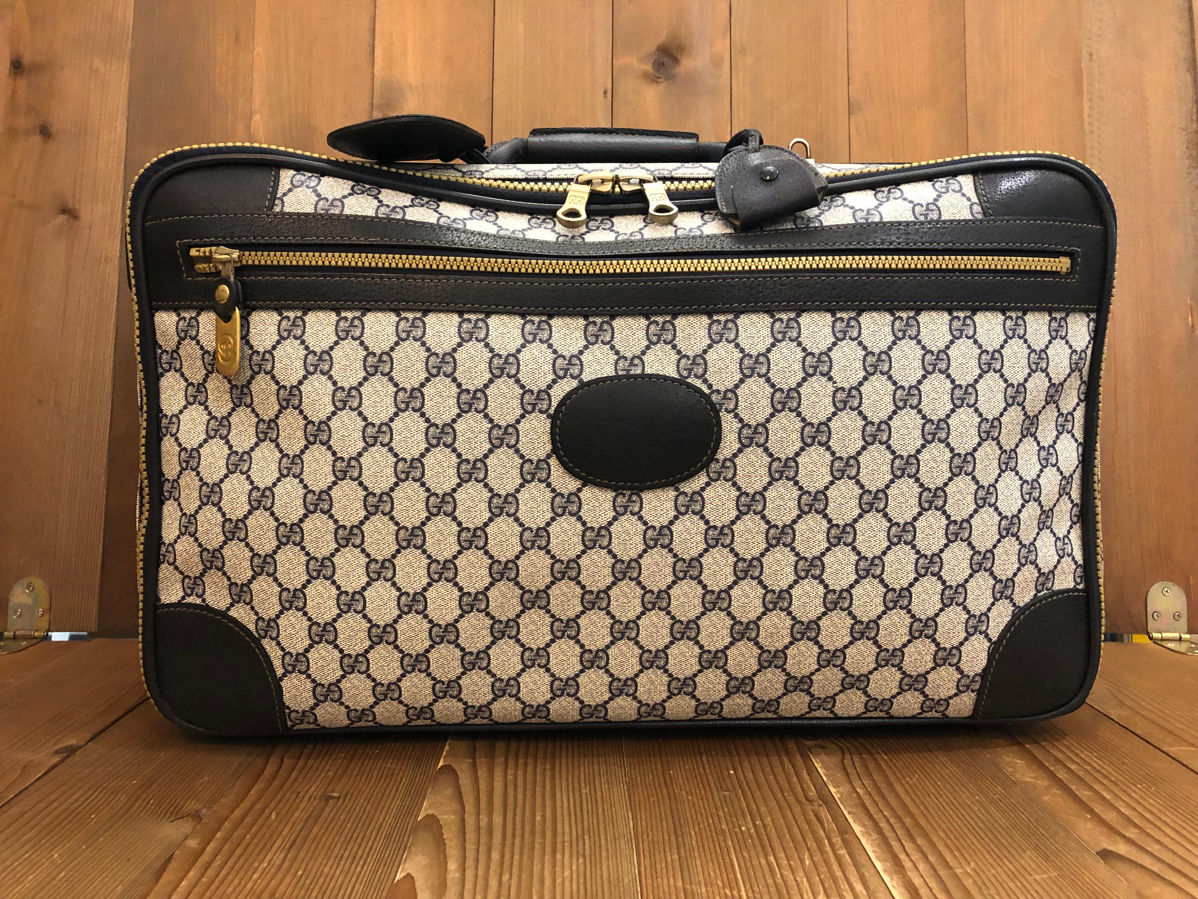 This vintage GUCCI Web softsided suitcase is crafted of Gucci's GG monogram coated canvas in navy trimmed with navy leather and decorated with Gucci's iconic Web stripe in blue/red. This softsided suitcase features two zip around compartments, one