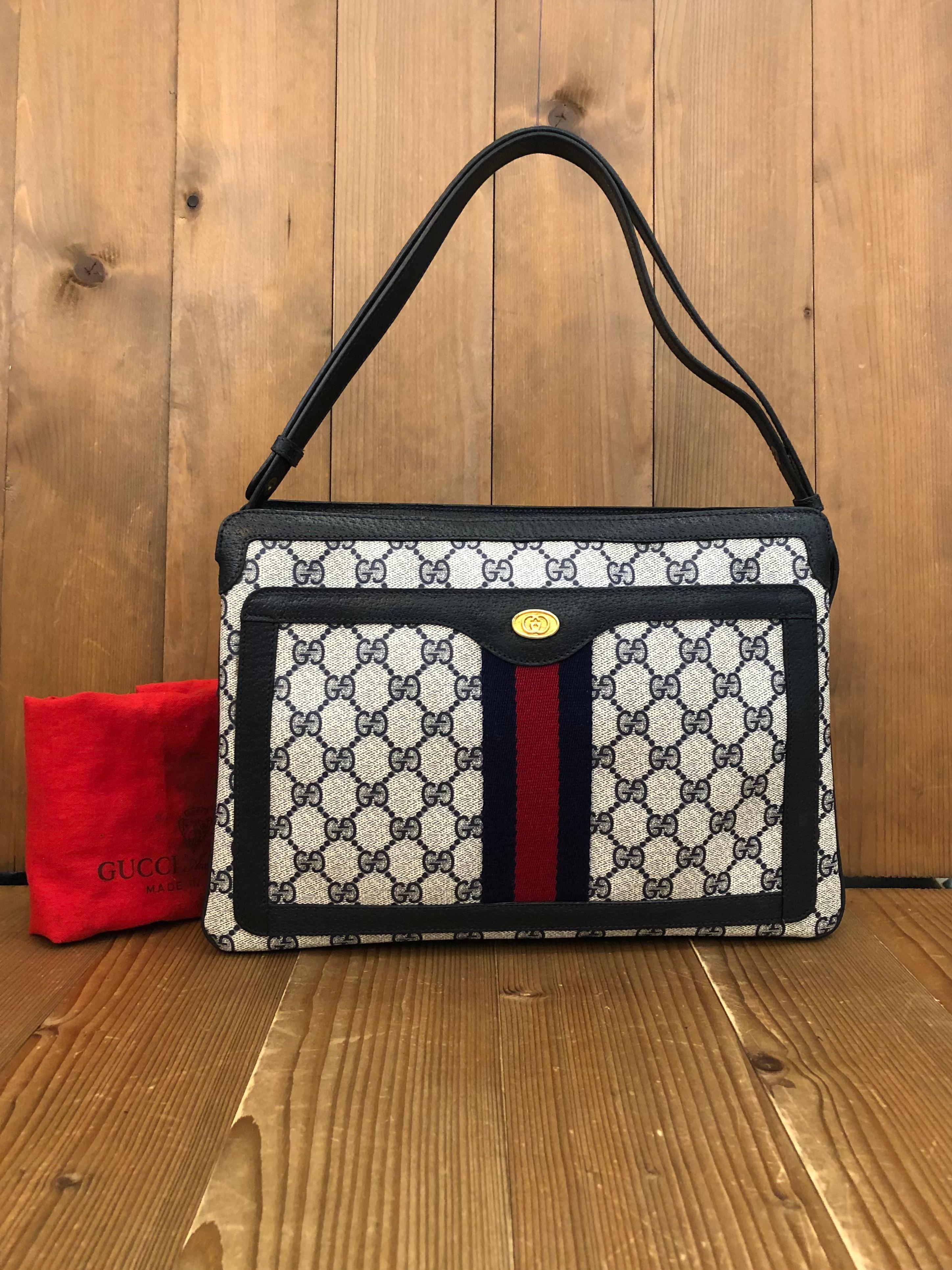 This vintage GUCCI web shoulder bag from the 1980s is crafted of navy monogram canvas and leather in navy featuring Guccis iconic navy/red web. This shoulder bag features three main compartments with one front open pocket and one interior zip