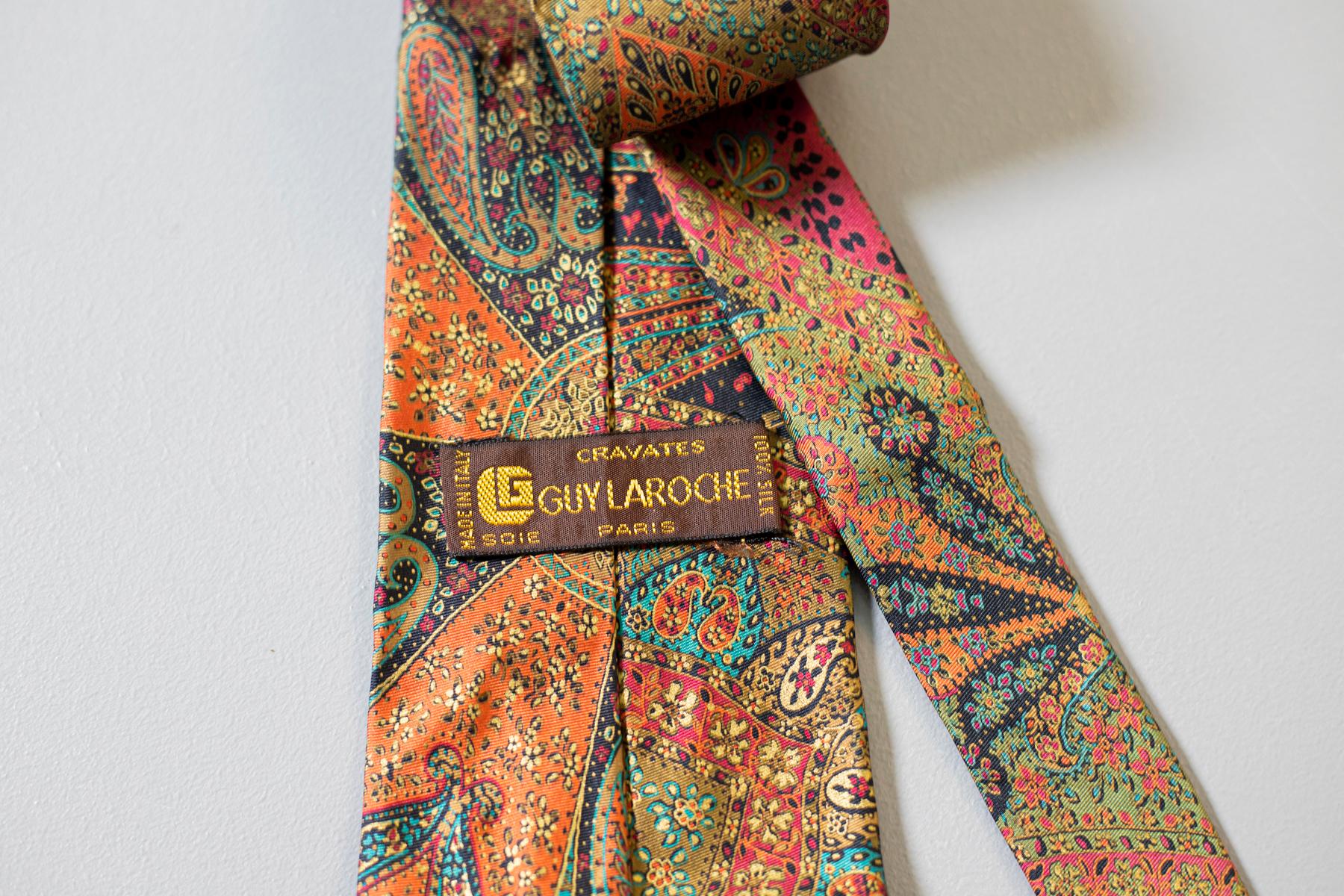 Multicolore, voyante et créative : cette cravate tout en soie conçue par Guv Laroche et fabriquée en Italie est un excellent accessoire. Décorée d'un motif paisley en orange, rouge, vert, bleu et jaune, cette cravate est parfaite pour tous ceux qui