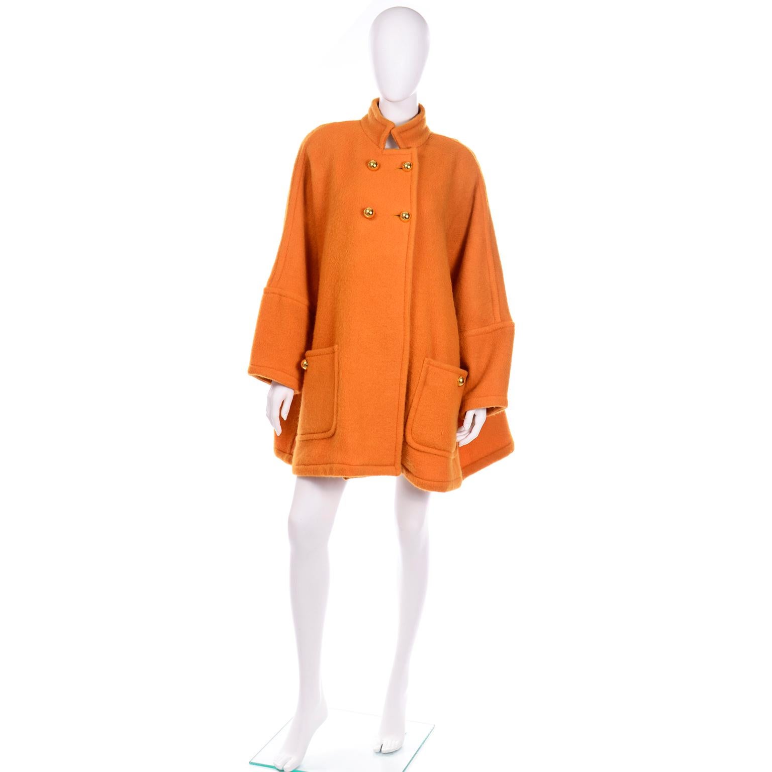 This vintage Guy Laroche coat is in a tangerine shade of orange mohair and wool blend with round dome gold buttons. There are two functional front pockets with gold button closures and shoulder pads for structure. The batwing sleeves add so much