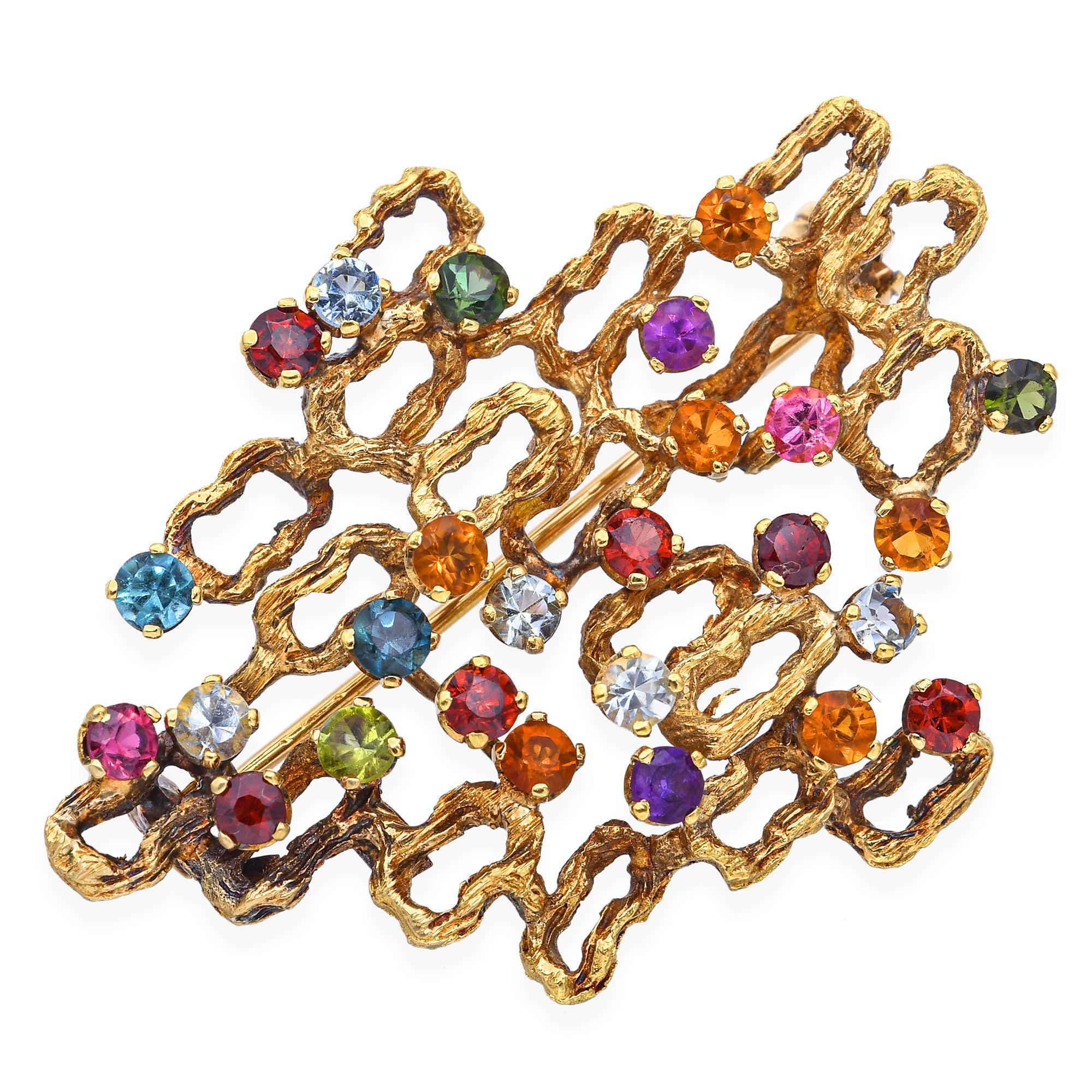 This enchanting vintage brooch is crafted in rich 18k yellow gold and designed in the form of a graceful vine. Adorned with an array of vibrant multi-colored gemstones, each stone is nestled like a leaf or bud along the winding gold branches. The
