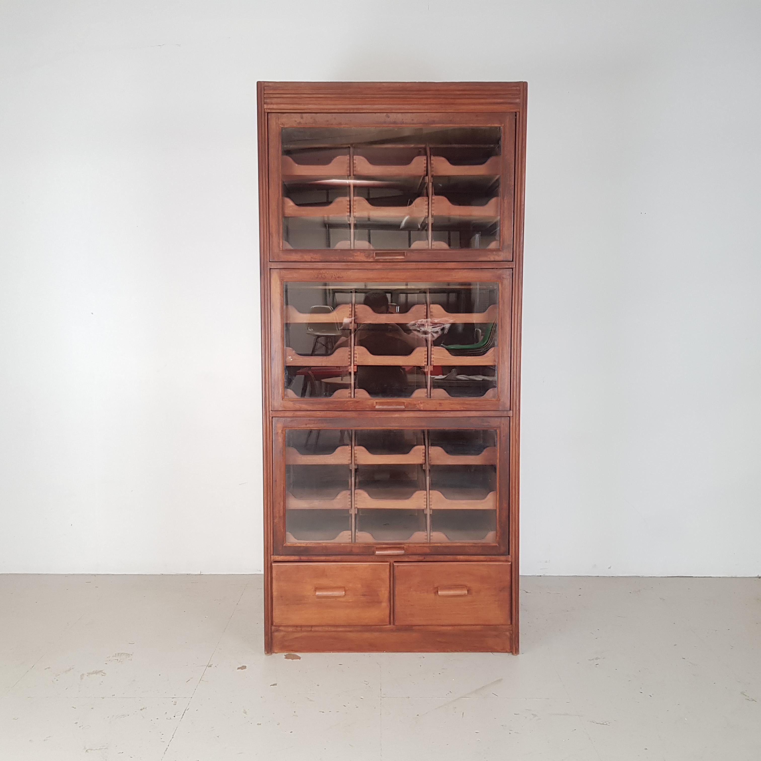 Lovely vintage 4 section haberdashery shop cabinet from the middle of the last century.

It has 3 upper glass fronted sections with nine pullout or pull-out drawers in each (bottom 6 are deeper than the top 3) and two solid drawers at the